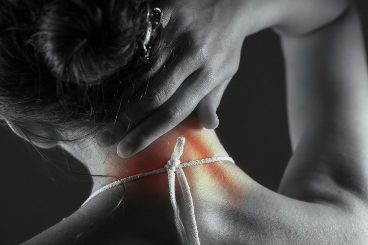 Person sitting on the edge of a bed holding their lower back, illustrating chronic discomfort