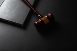 Wooden gavel resting on a dark surface next to book