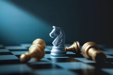 A white knight chess piece stands over fallen gold pieces.