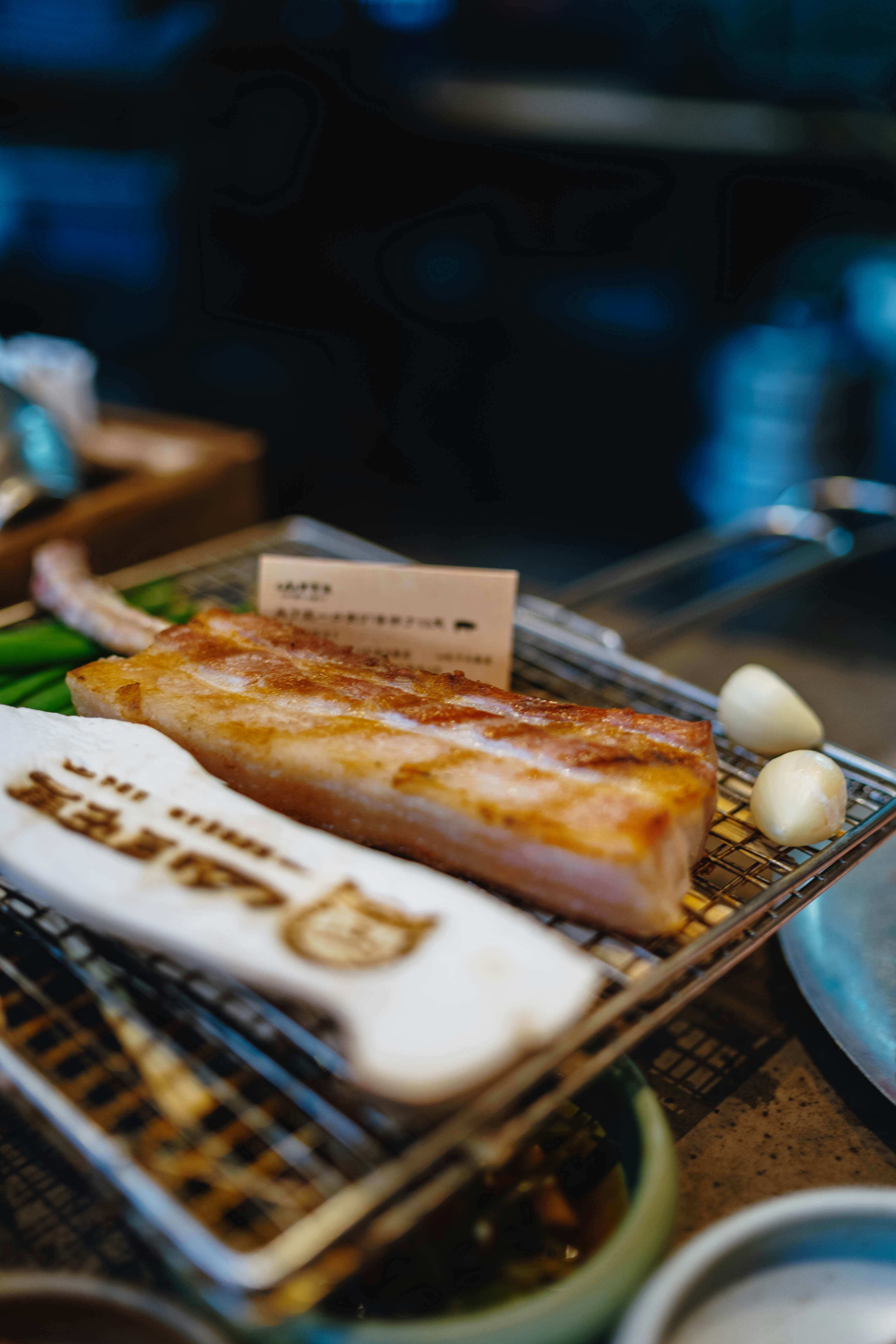 Raw pork belly on a grill with garlic.