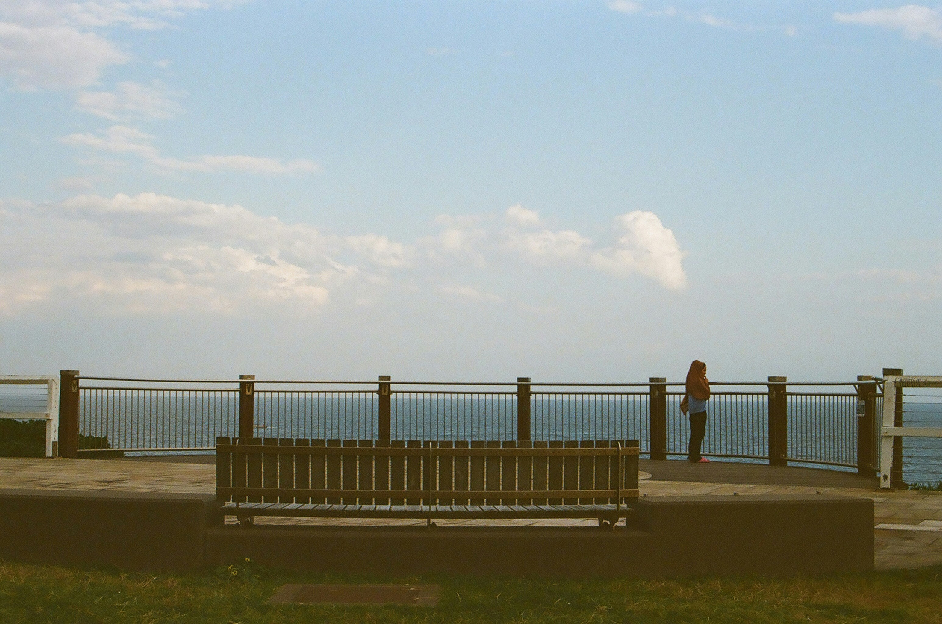Person looking out at the ocean from a scenic overlook.