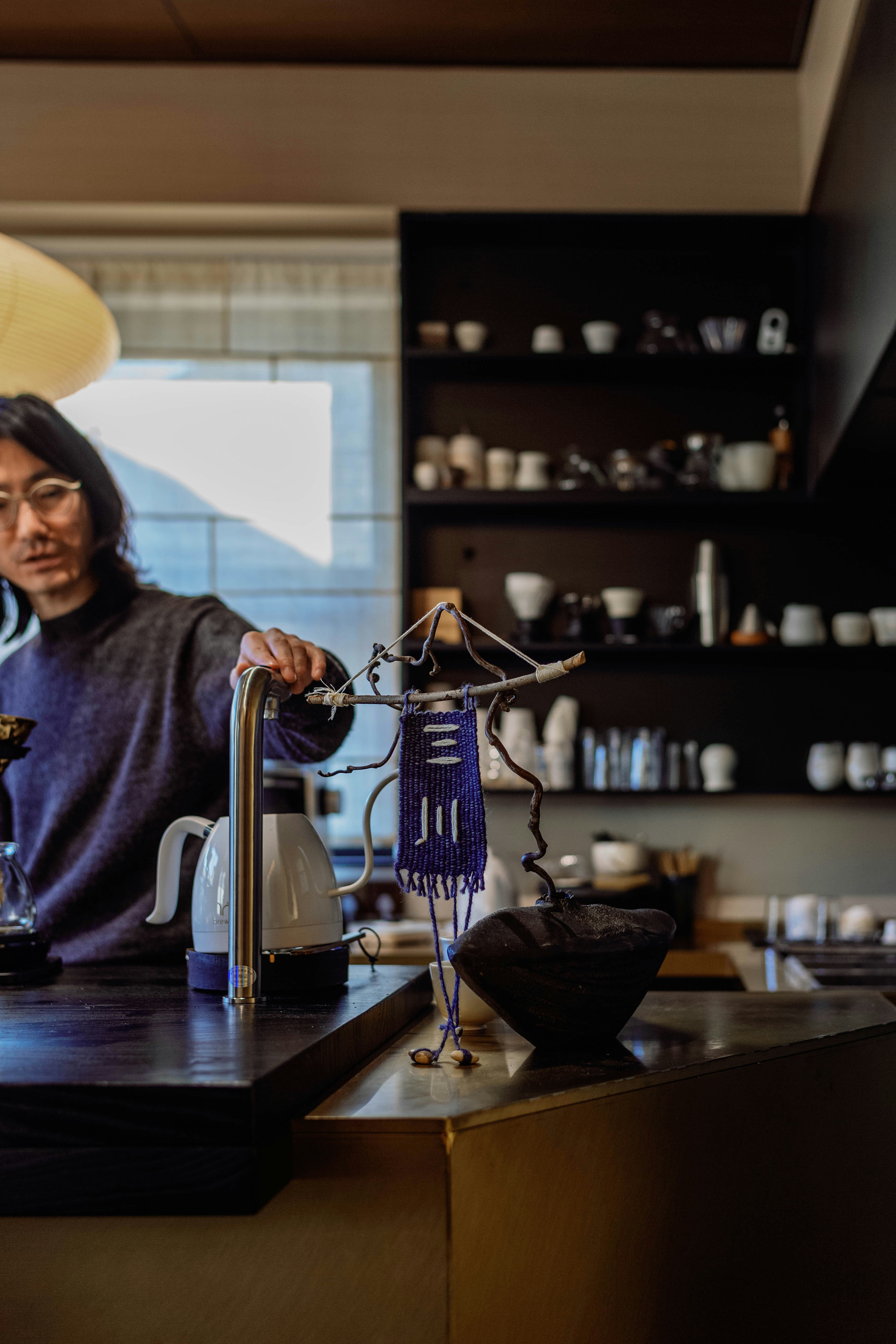 Man preparing coffee behind a counter with shelves