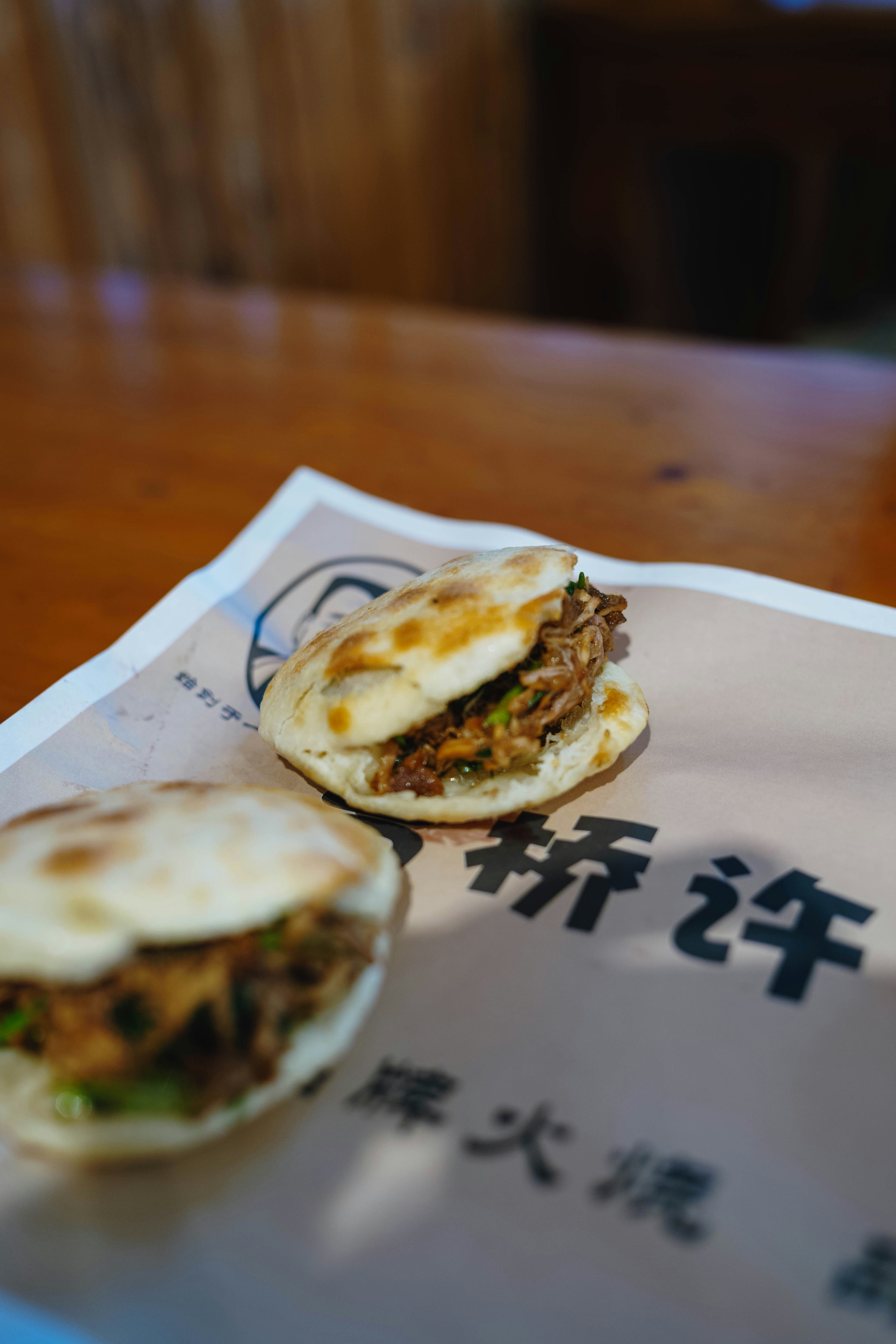 Two savory meat-filled flatbread sandwiches on paper