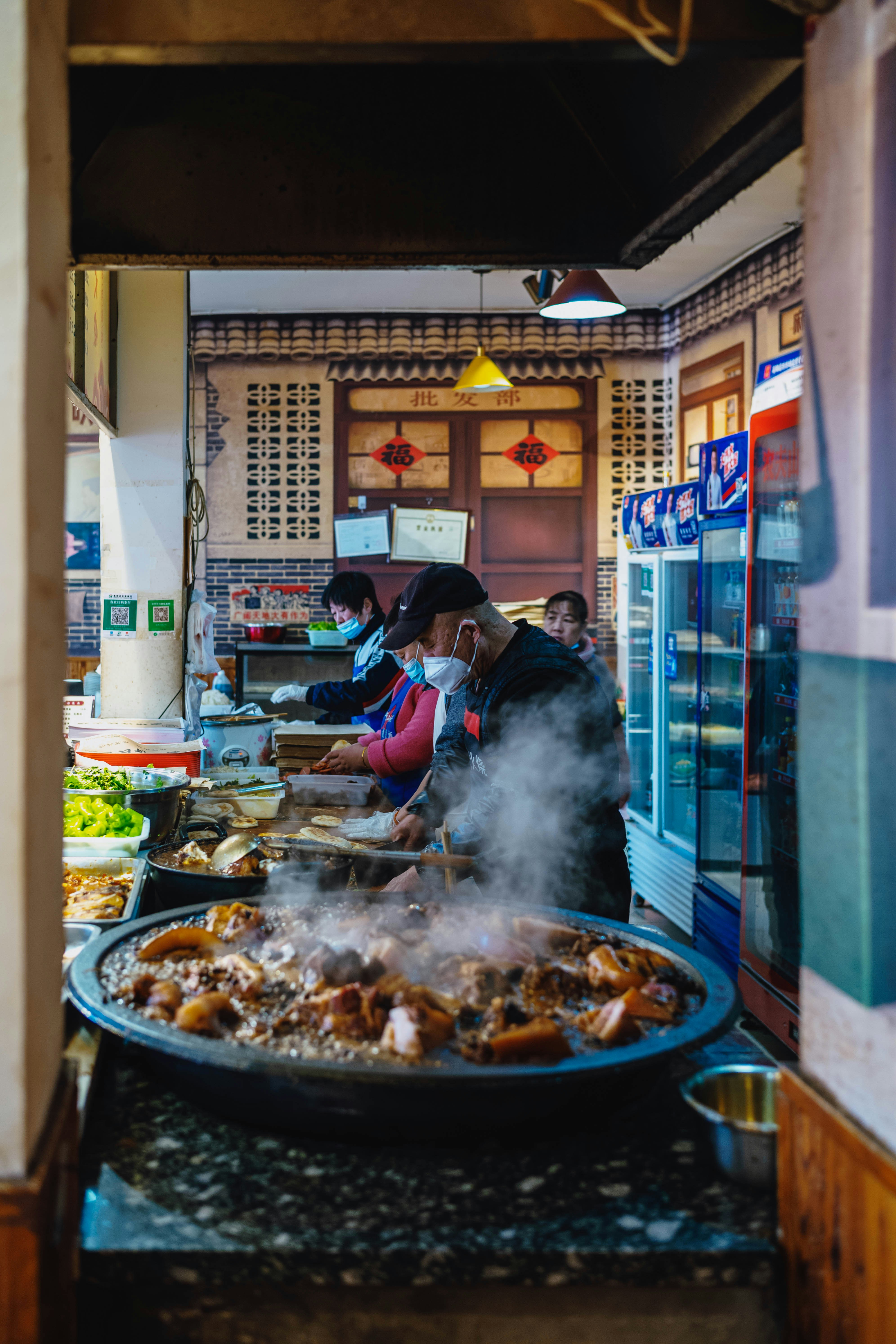 People cooking meat in a large pot with steam.