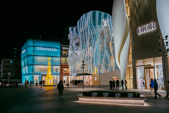Luxury brand stores illuminated at night with people walking