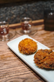 Two fried croquettes on a white plate