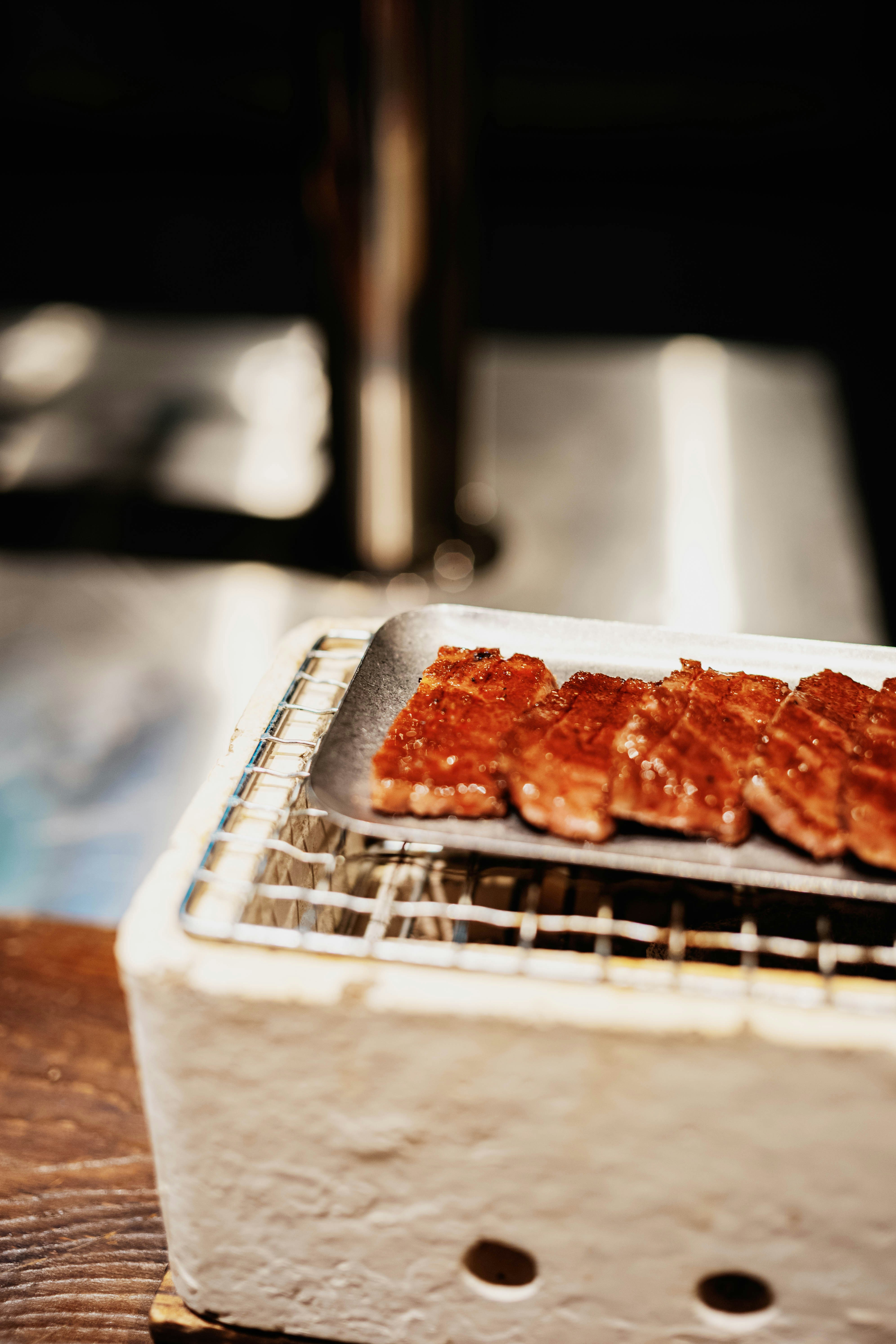 Slices of grilled meat cooking on a small grill.