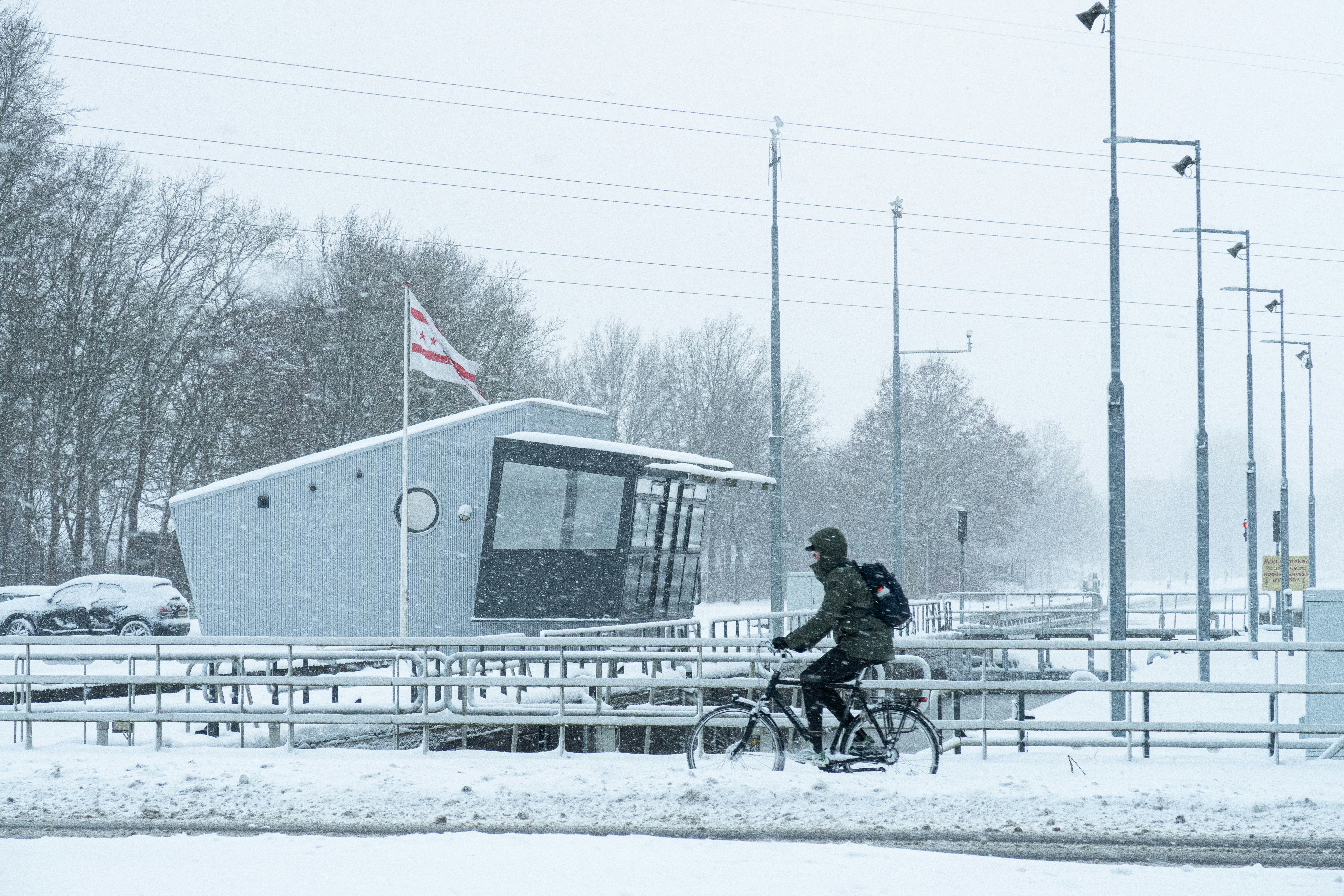 A person cycles past a building in a snowstorm.