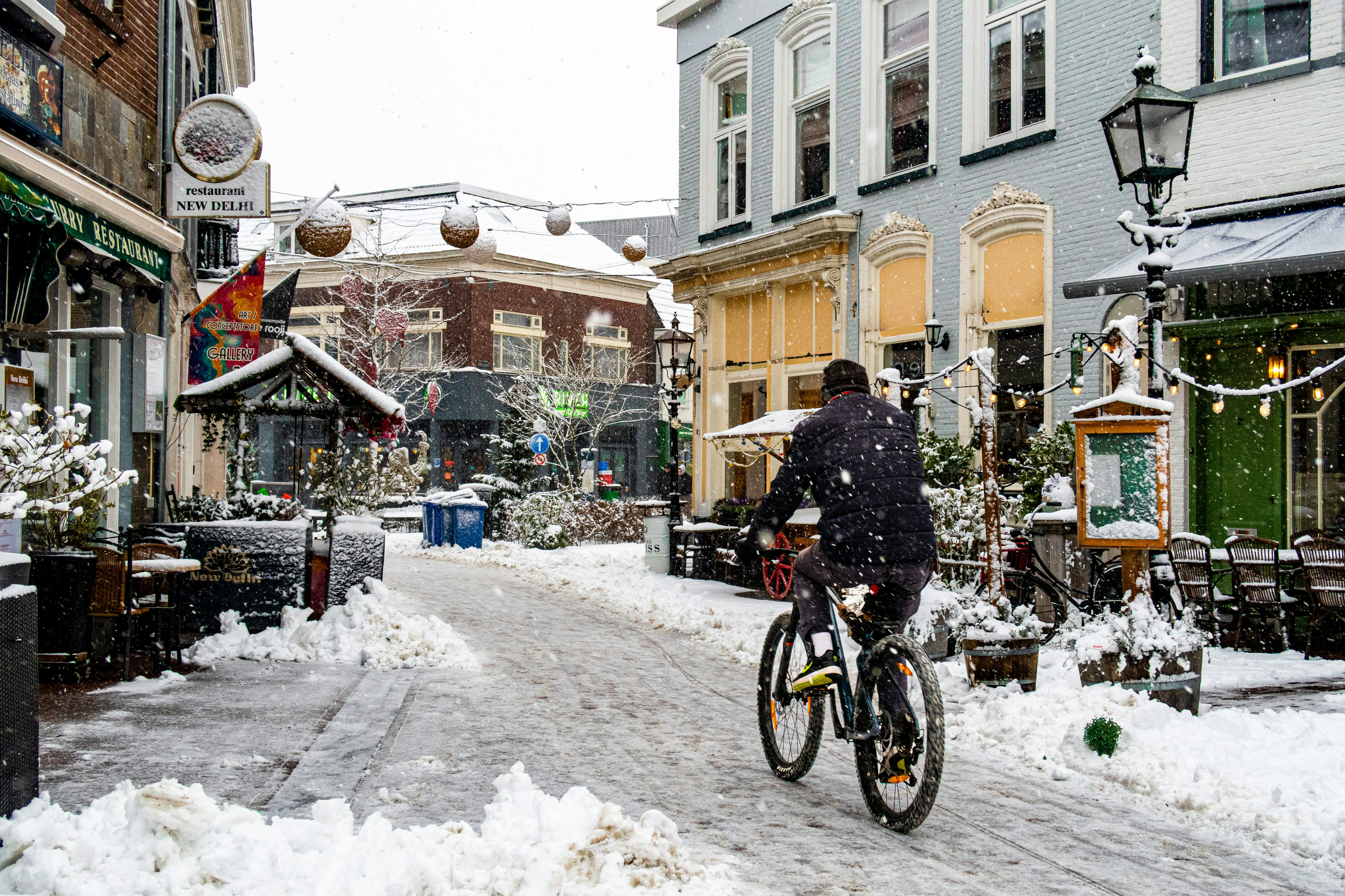 A person rides a bicycle on a snowy street.