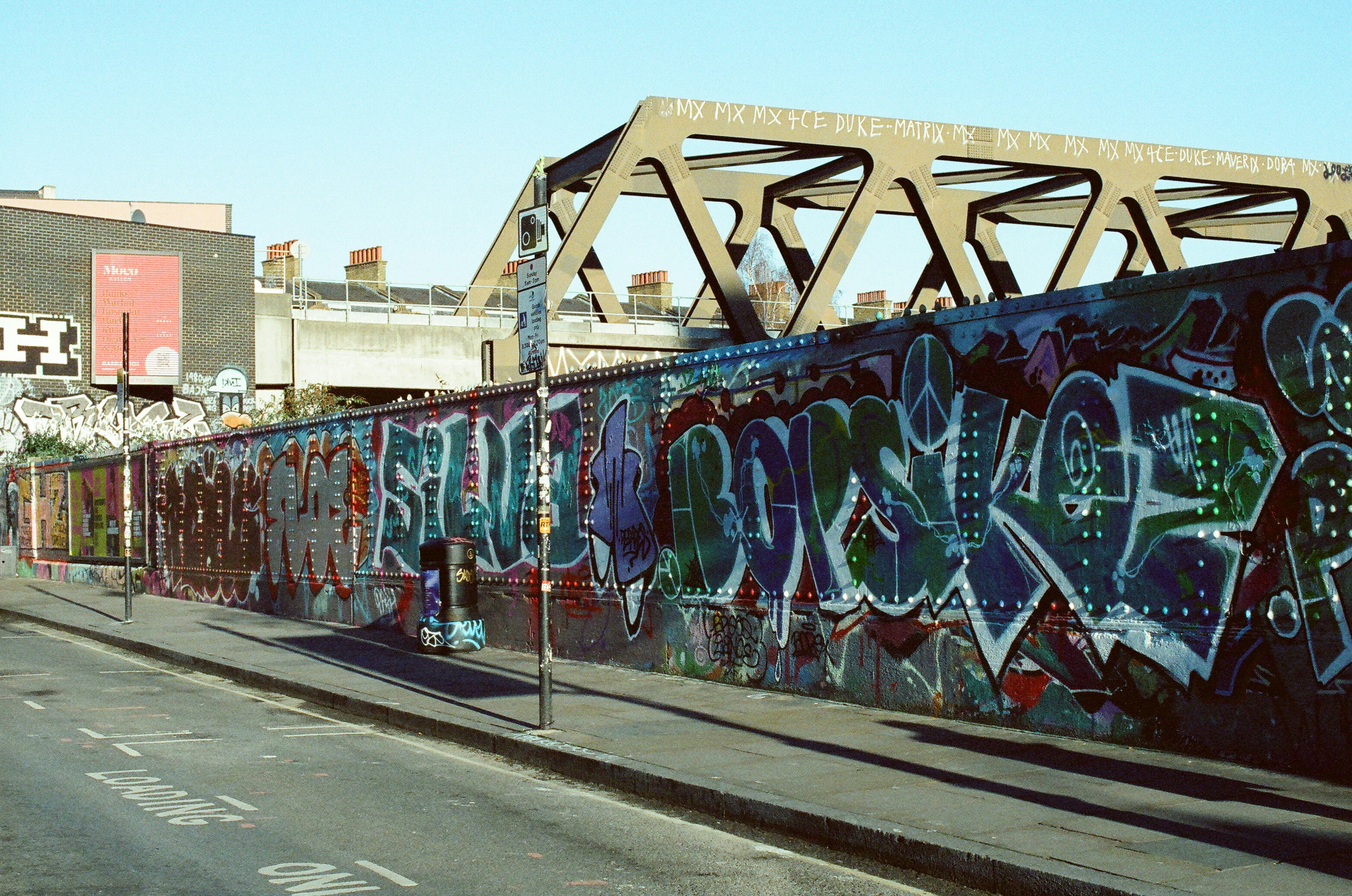 Graffiti art covers a long wall under a bridge. (Photo by Tanya Barrow on Unsplash)