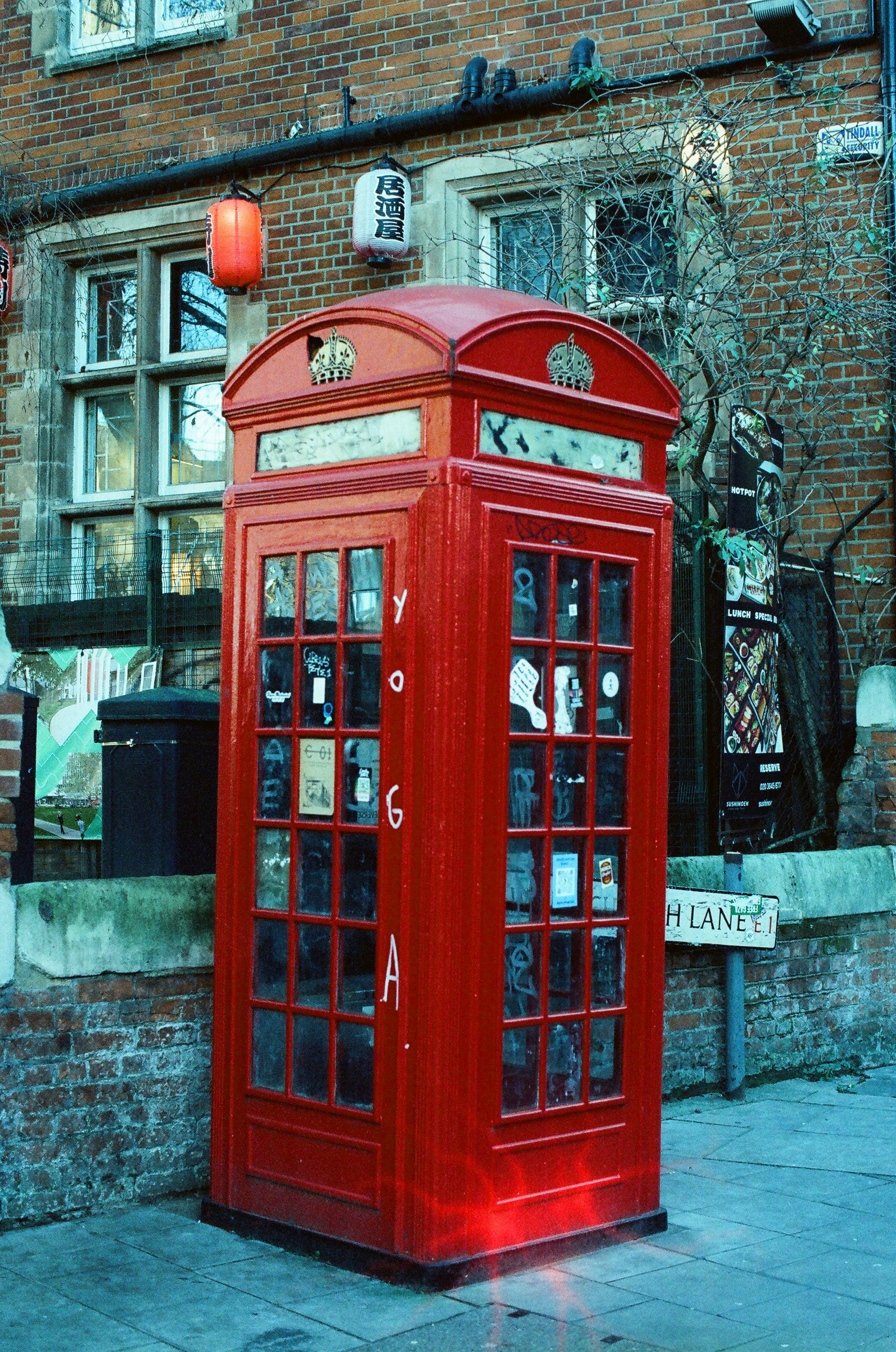 A classic red british telephone box on a street.