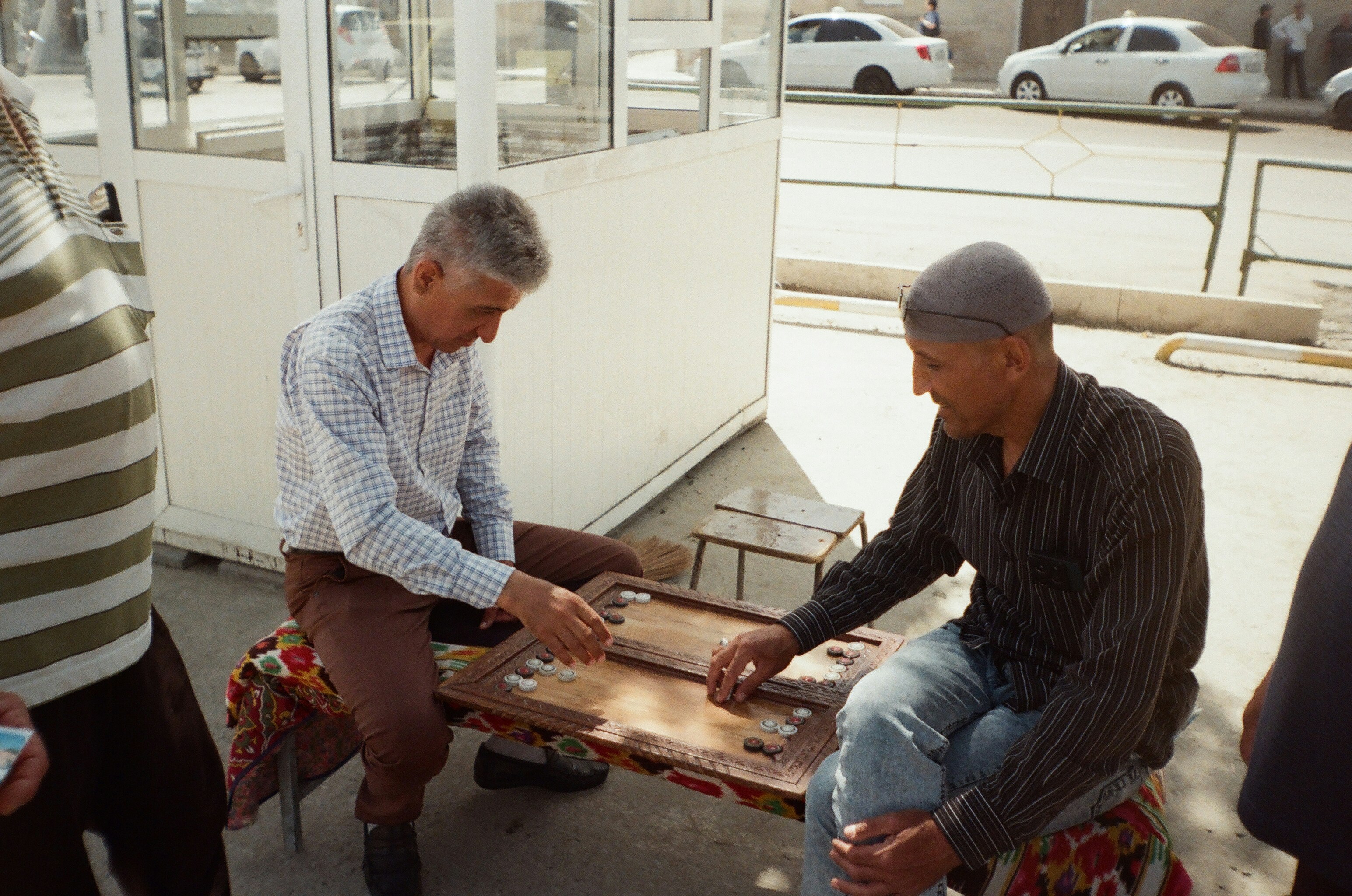 Two men playing backgammon outdoors on a table