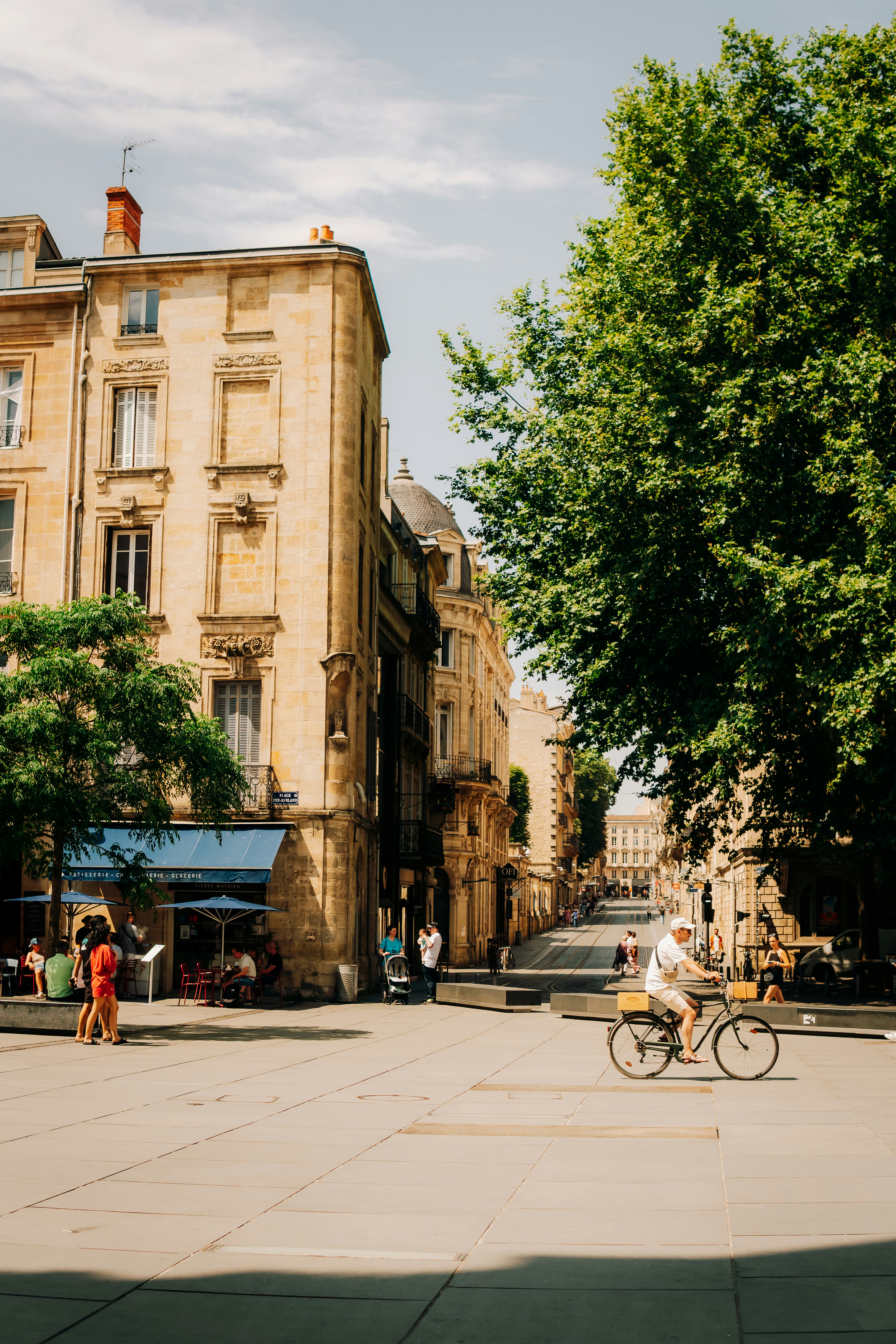 Man rides bicycle through sunny european square.
