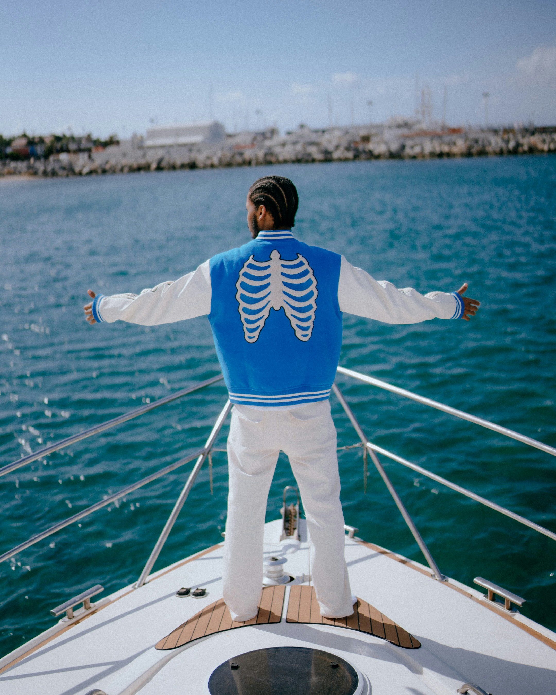 Man in blue jacket with skeleton design on yacht.