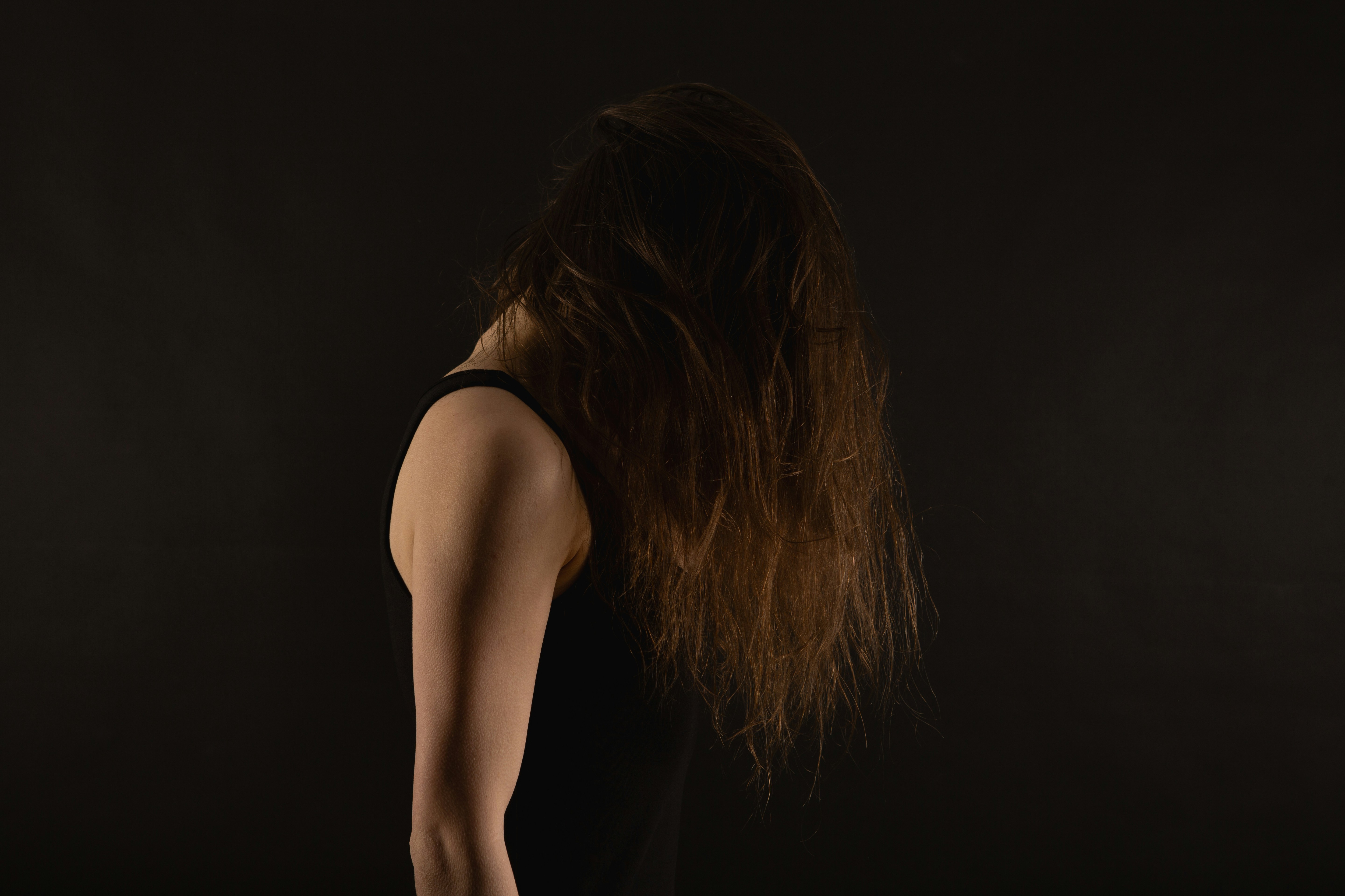 Woman with long brown hair against black background