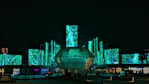 Modern building with glowing green abstract art displays at night
