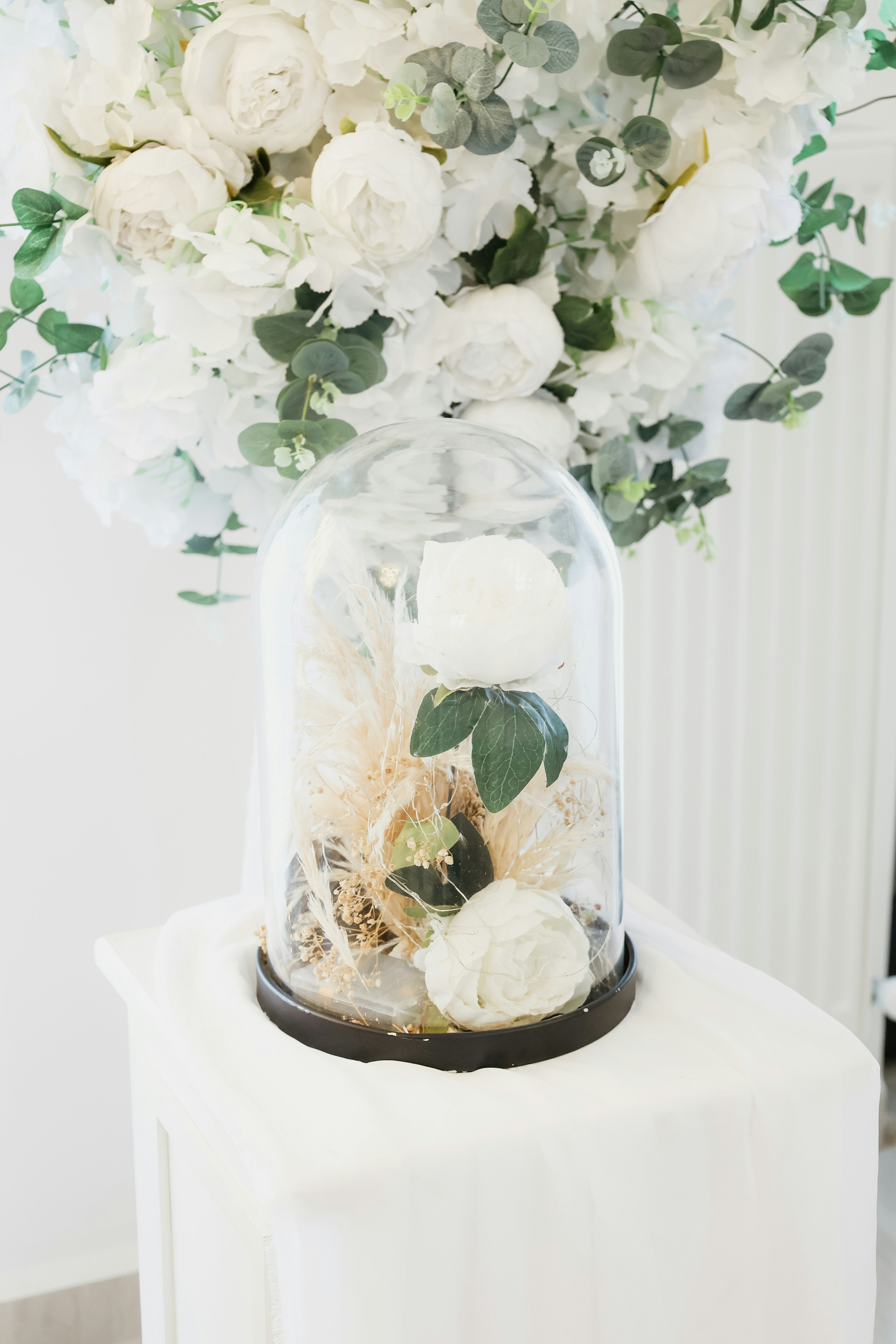 Weiße Rosen unter einer Glaskuppel mit Grün