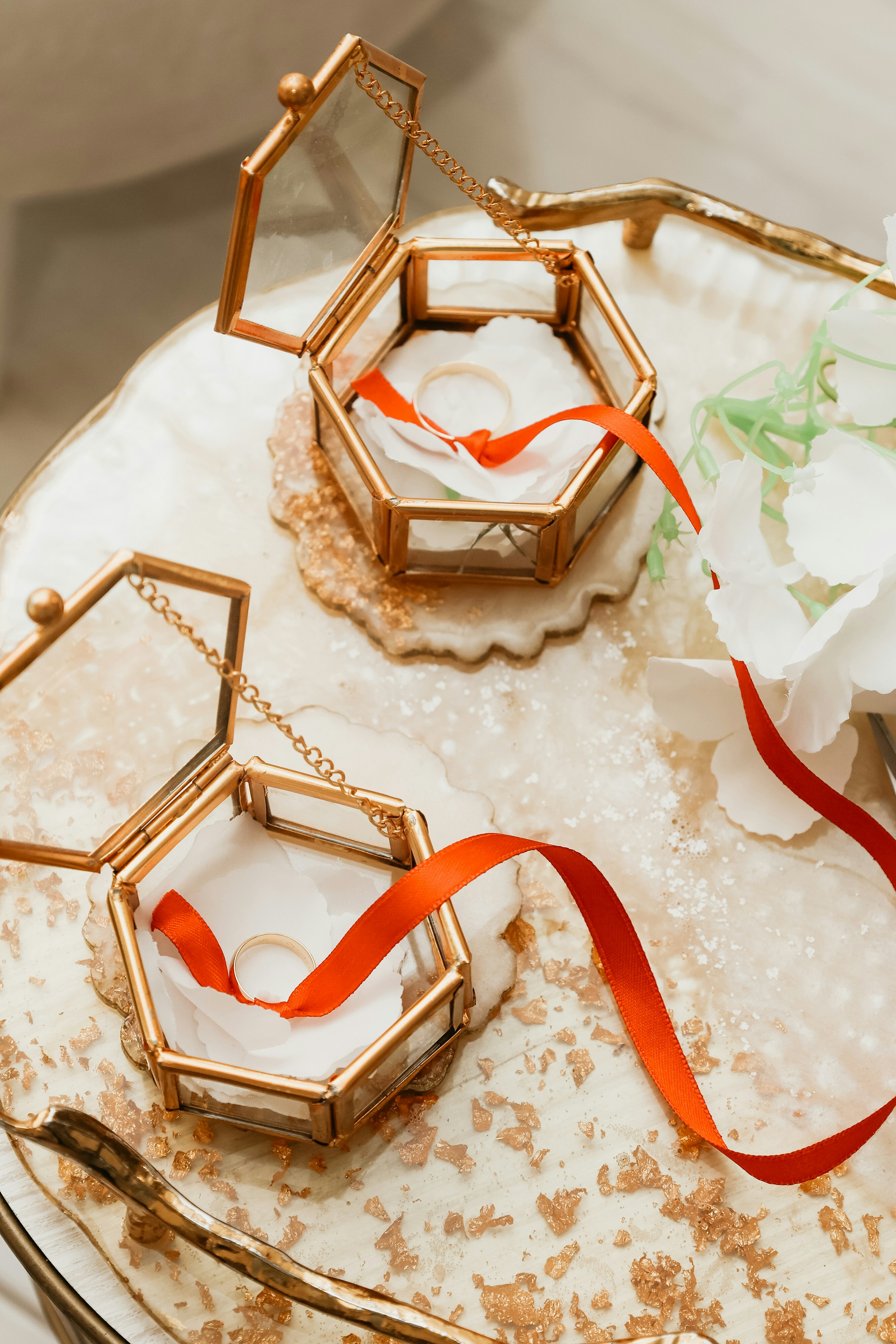 Two hexagonal glass ring boxes with red ribbons