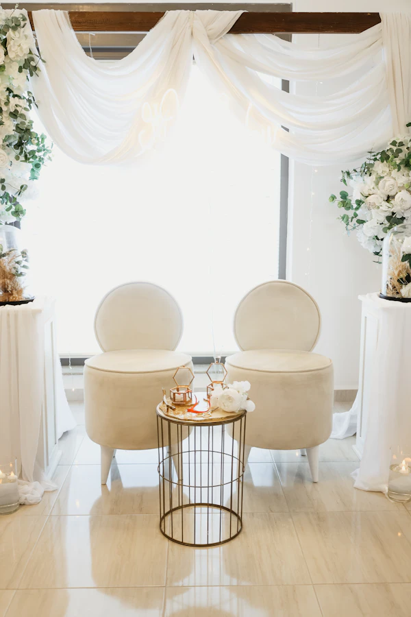 Nashville wedding venue - Elegant white chairs with a small table between them.