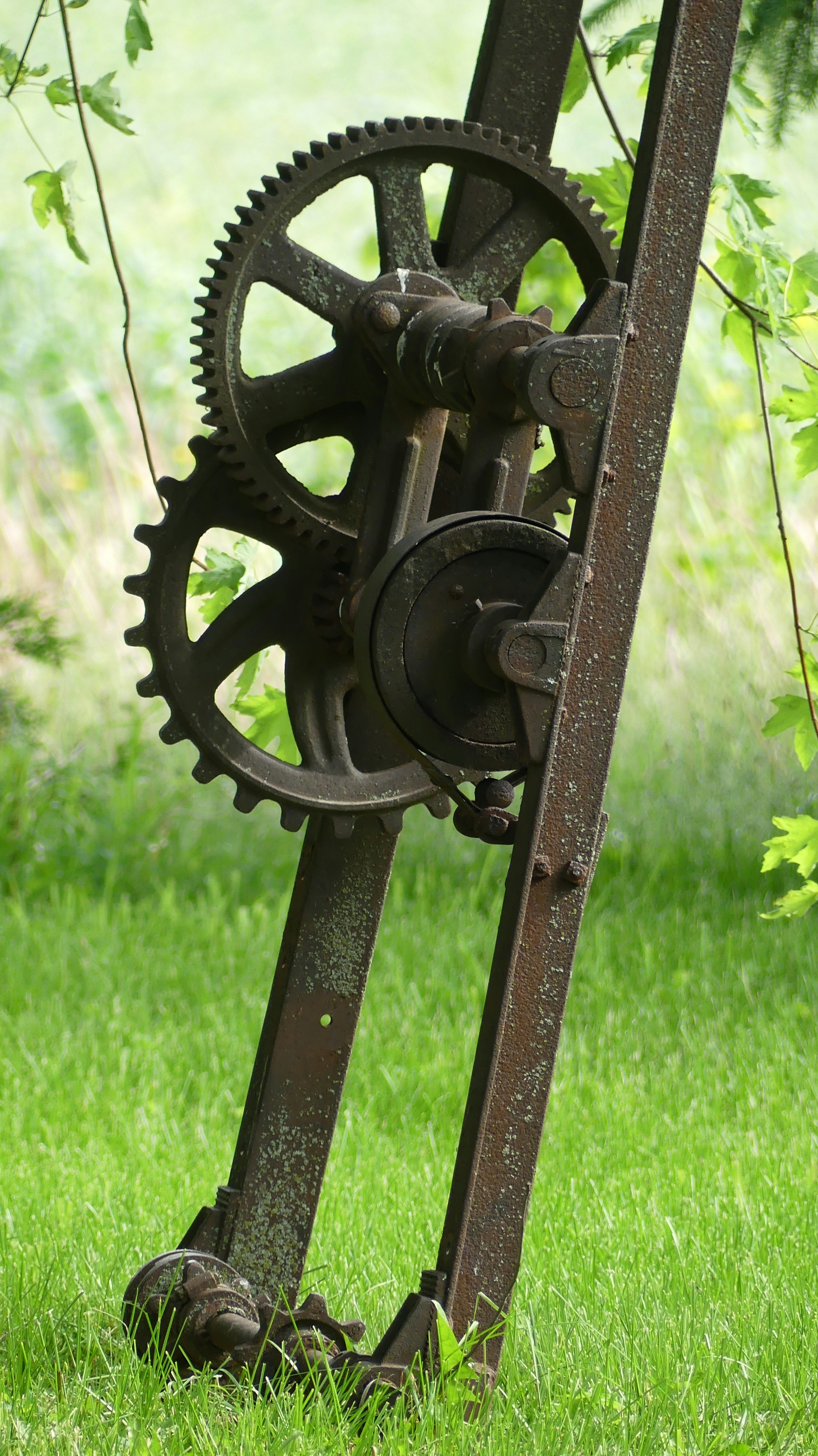 Engrenagens enferrujadas e máquinas de metal em um campo gramado.