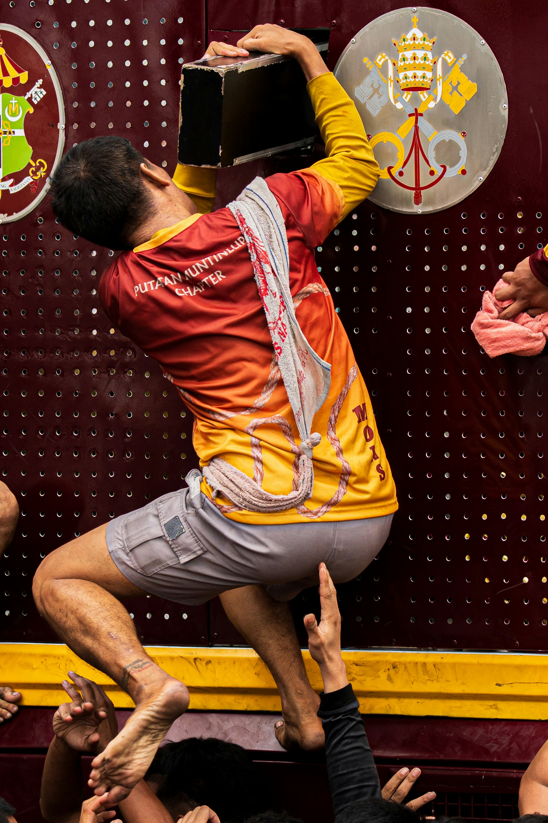 Man climbs structure with crowd lifting him up