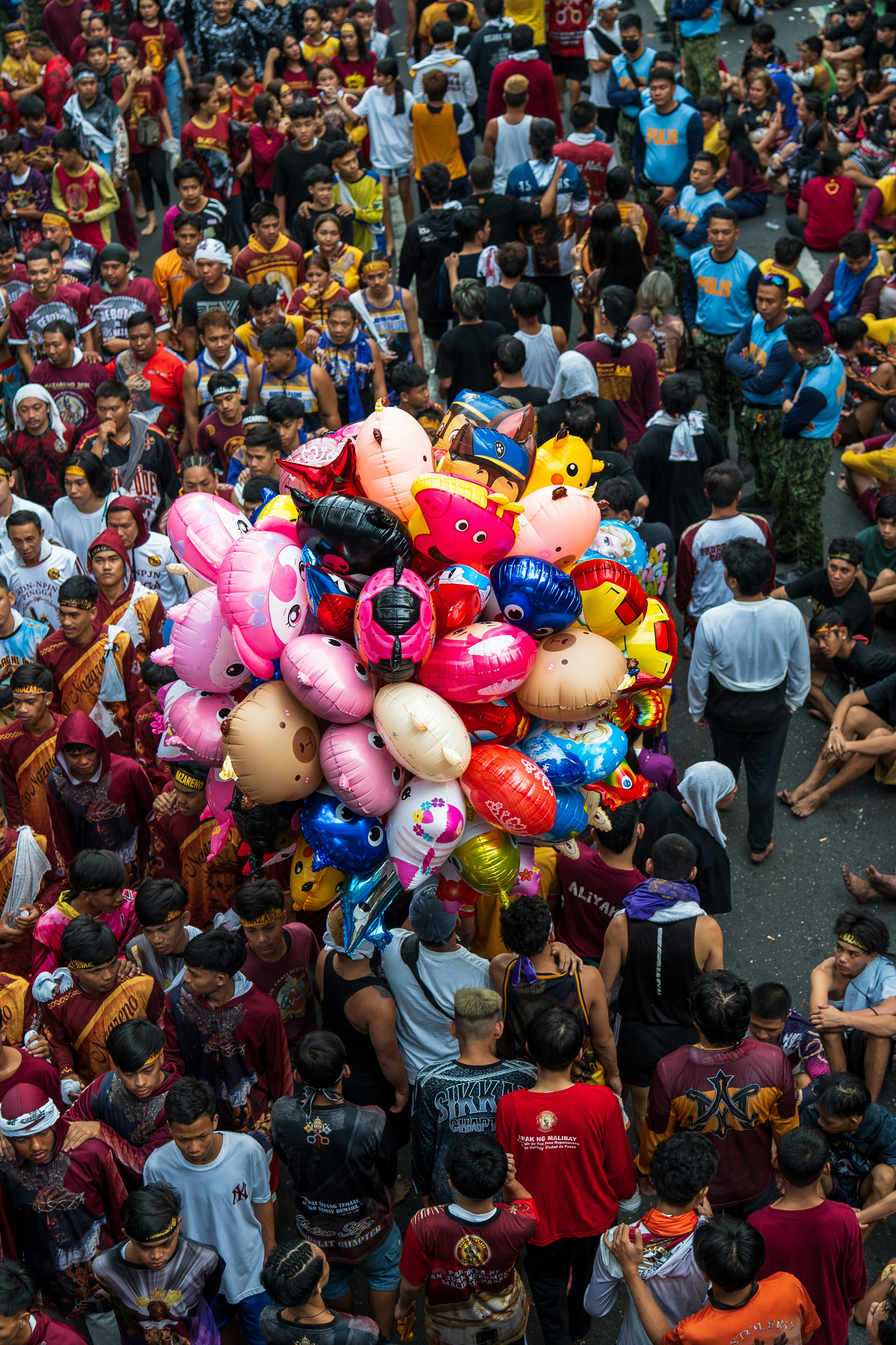 Crowd of people carrying colorful balloons during a festival.