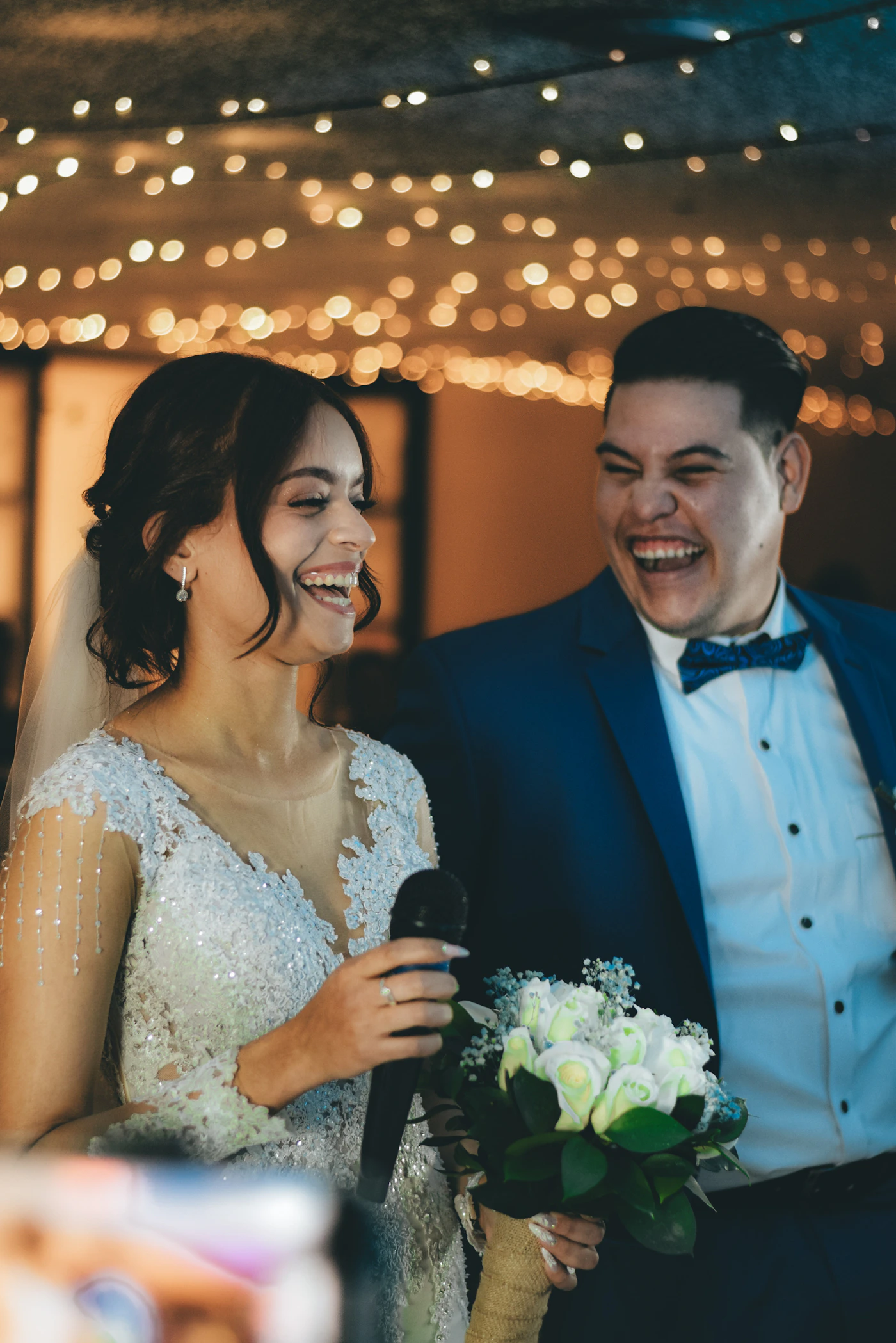 Bride and groom laughing together genuinely at their wedding reception in a candid and joyful moment