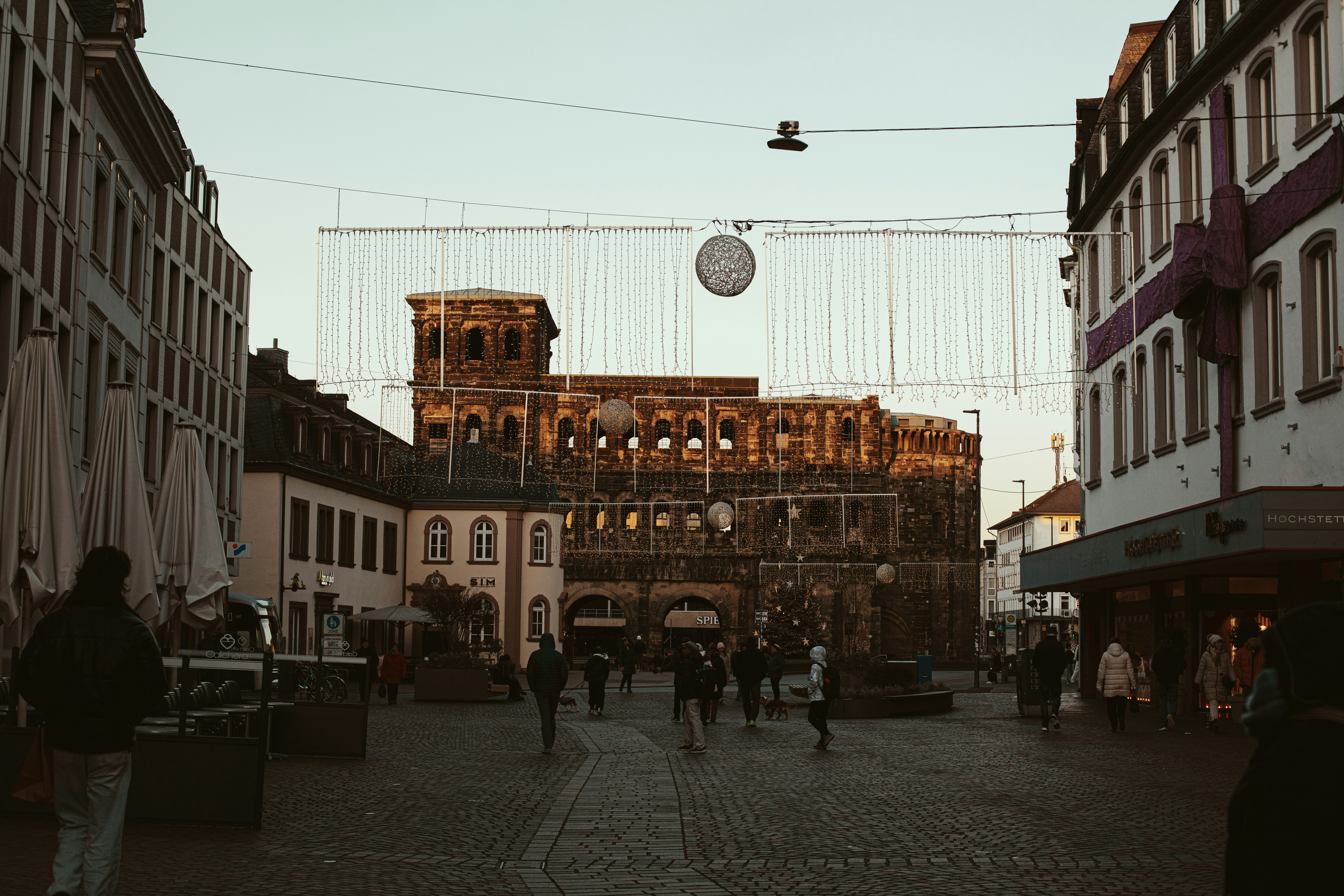 People walking in a european city square at sunset.
