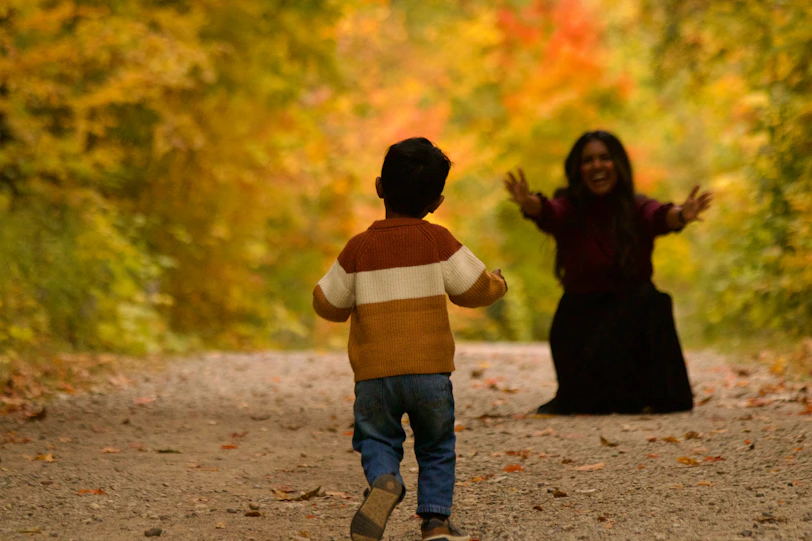 Child running towards a woman in autumn forest
