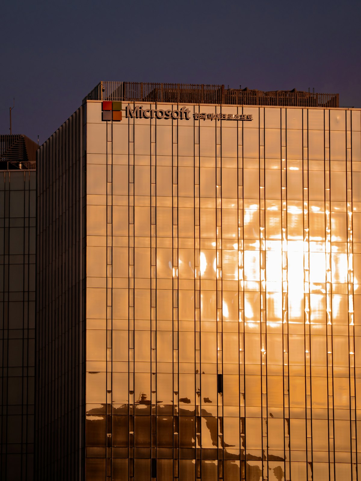 Microsoft building exterior at sunset representing the tech giant's AI challenges