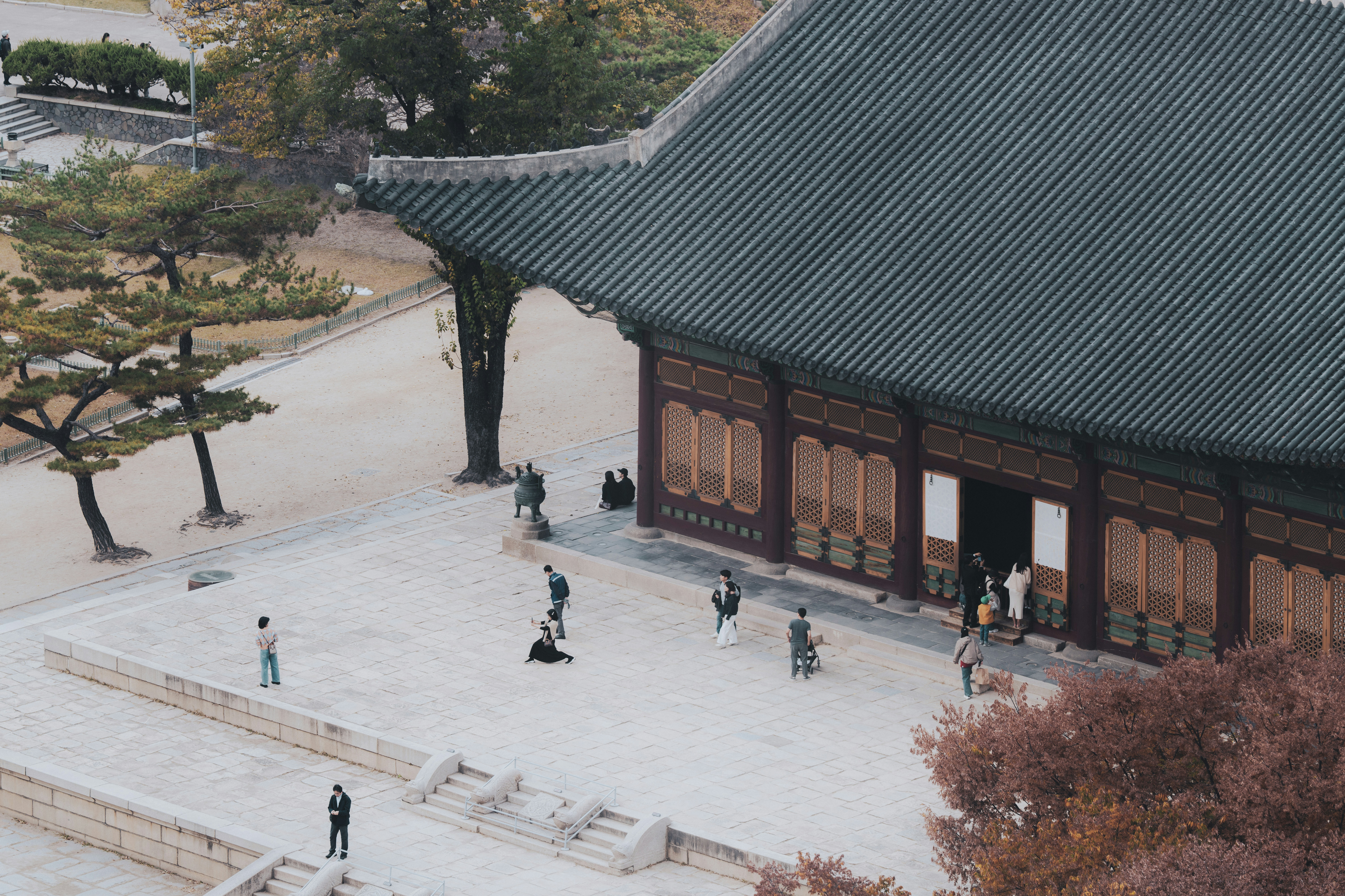 People gathered in courtyard of traditional korean palace building.