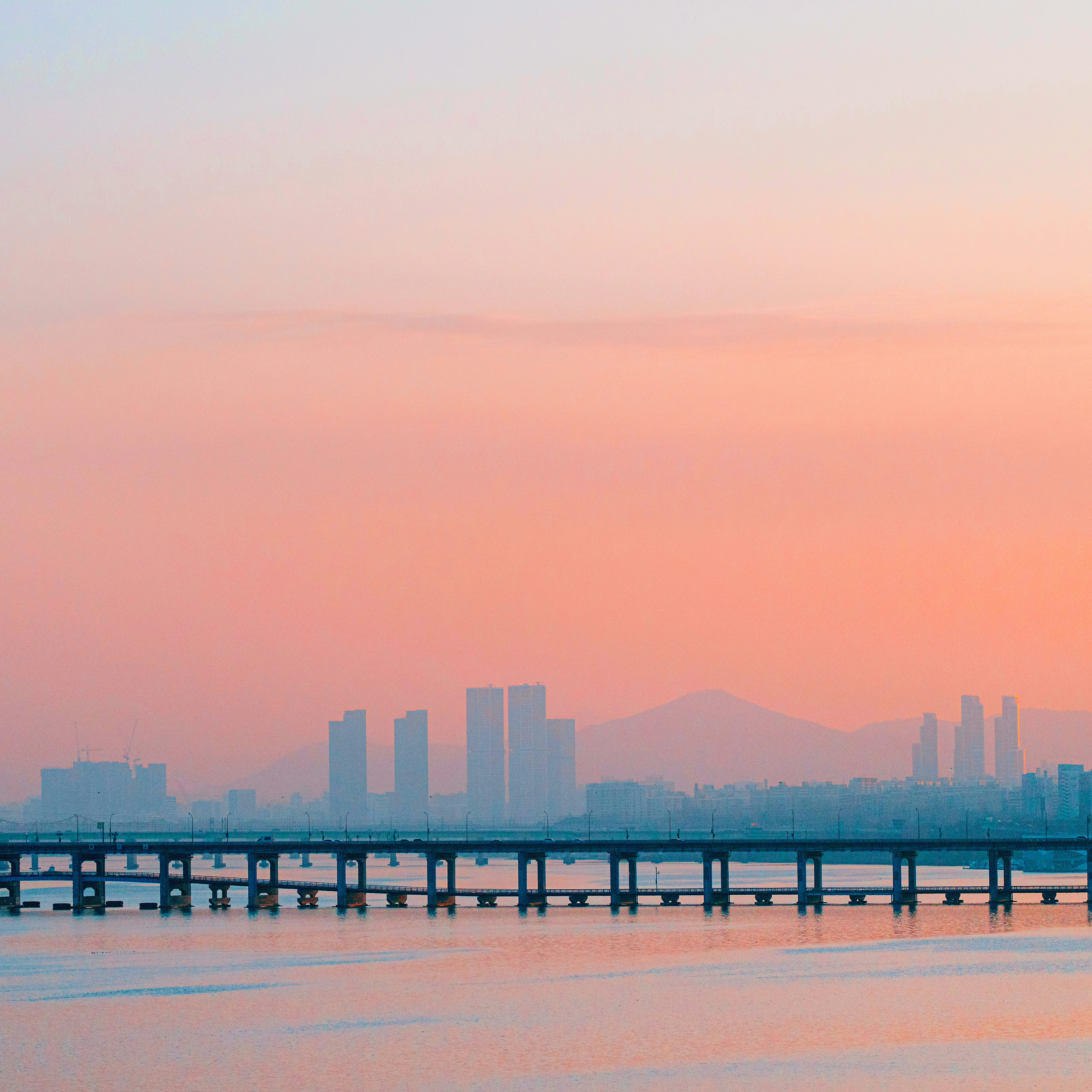 City skyline across a bridge at sunset.
