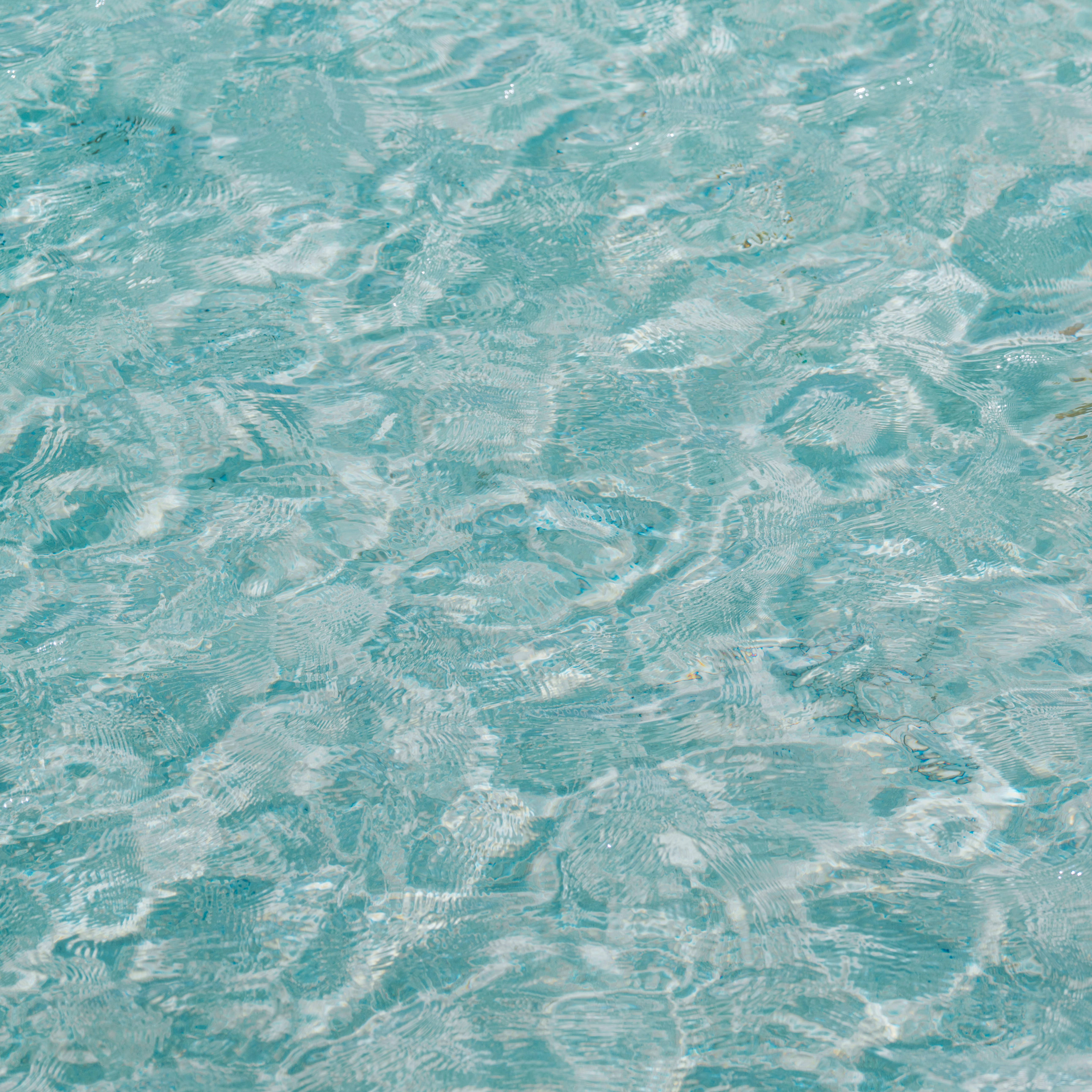 Rippling clear blue water surface with light reflections