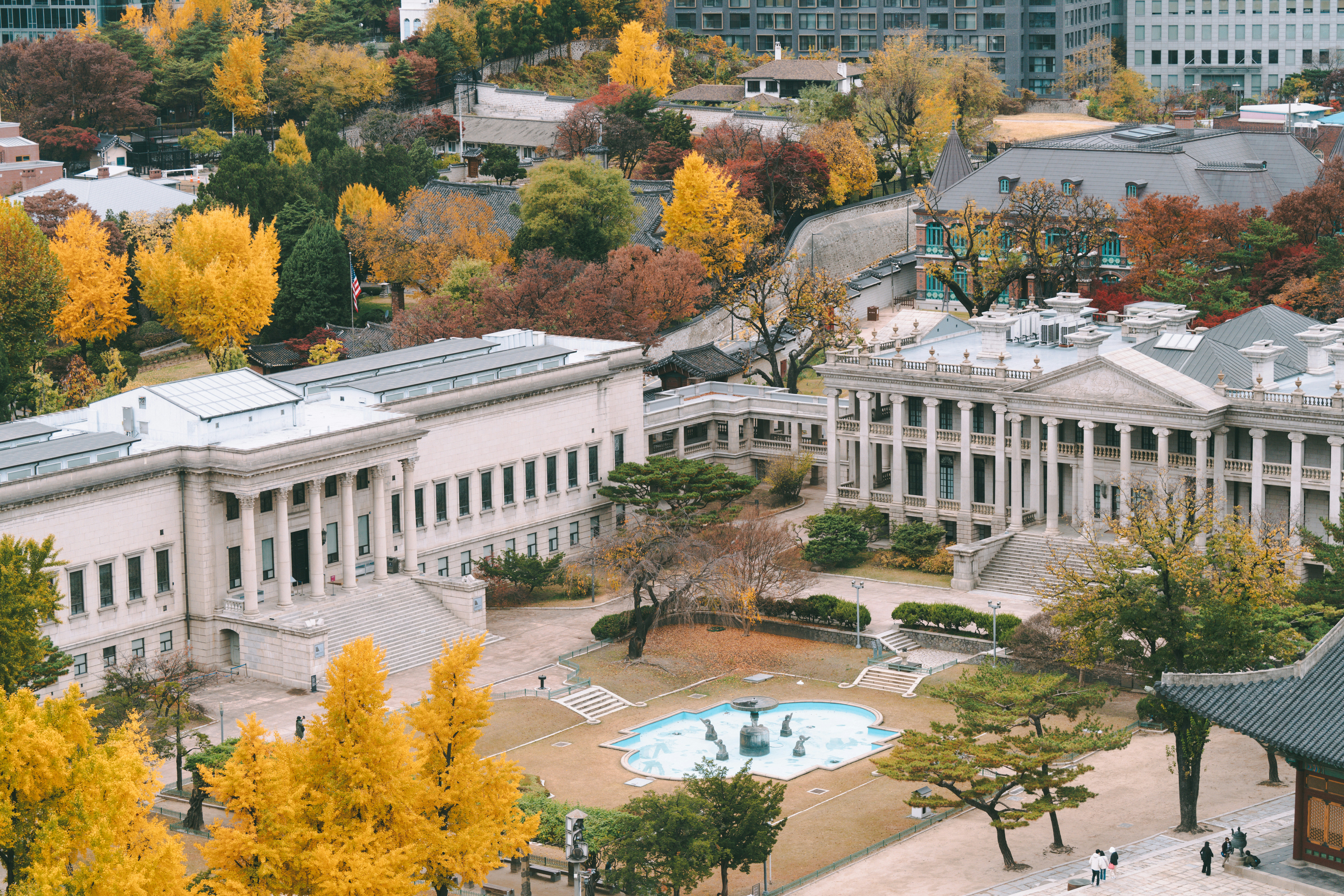 Autumn foliage surrounds historic buildings with a courtyard.