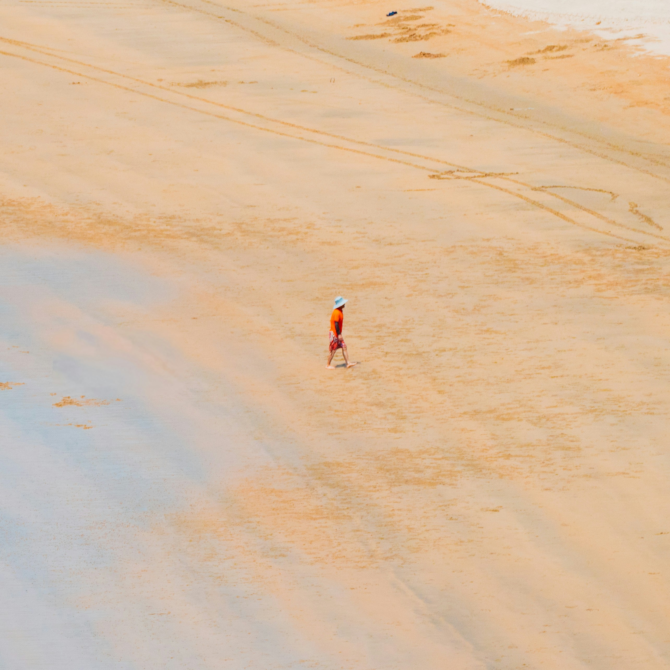 Lone person walking on a vast sandy beach.