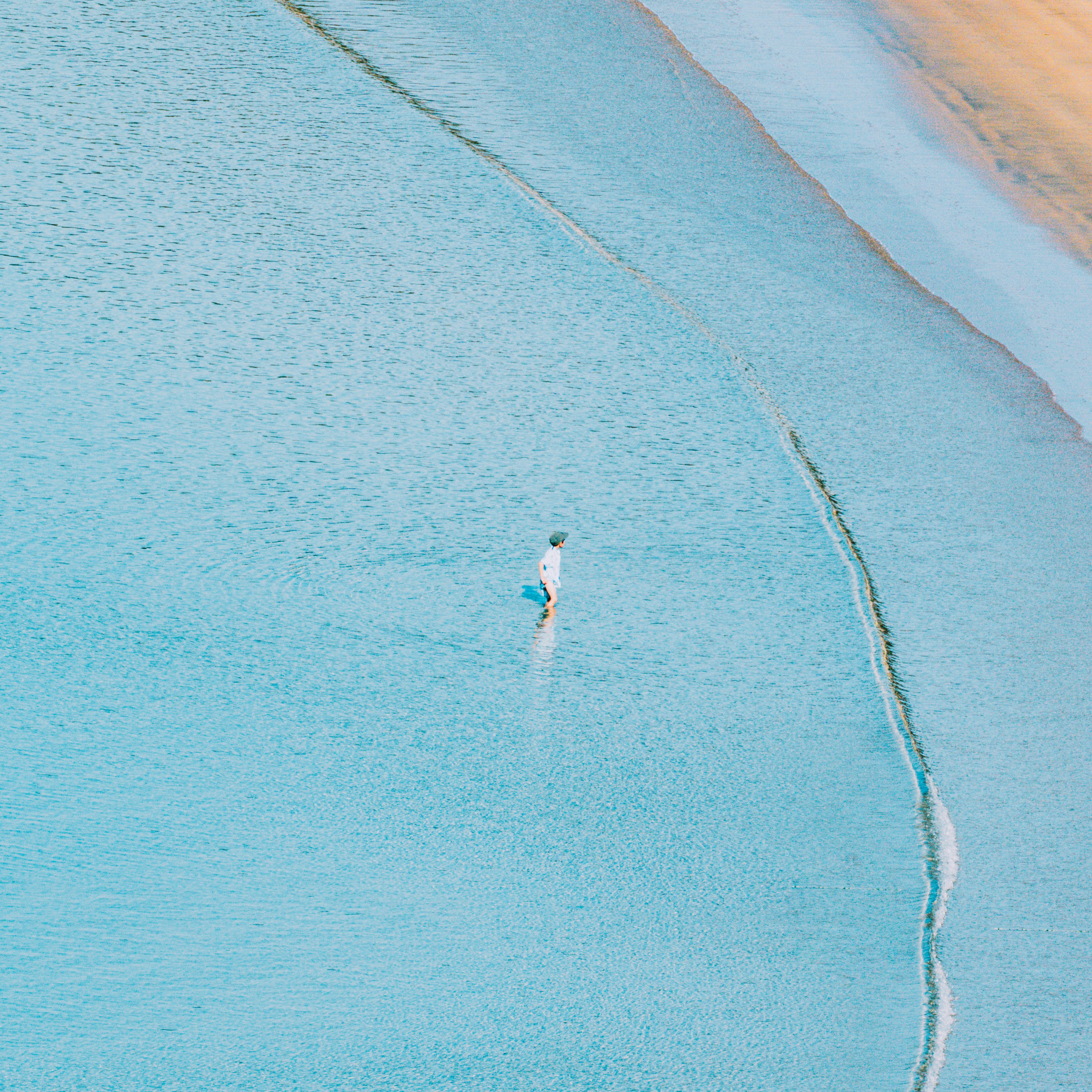 Man surfing on a calm, blue ocean wave.