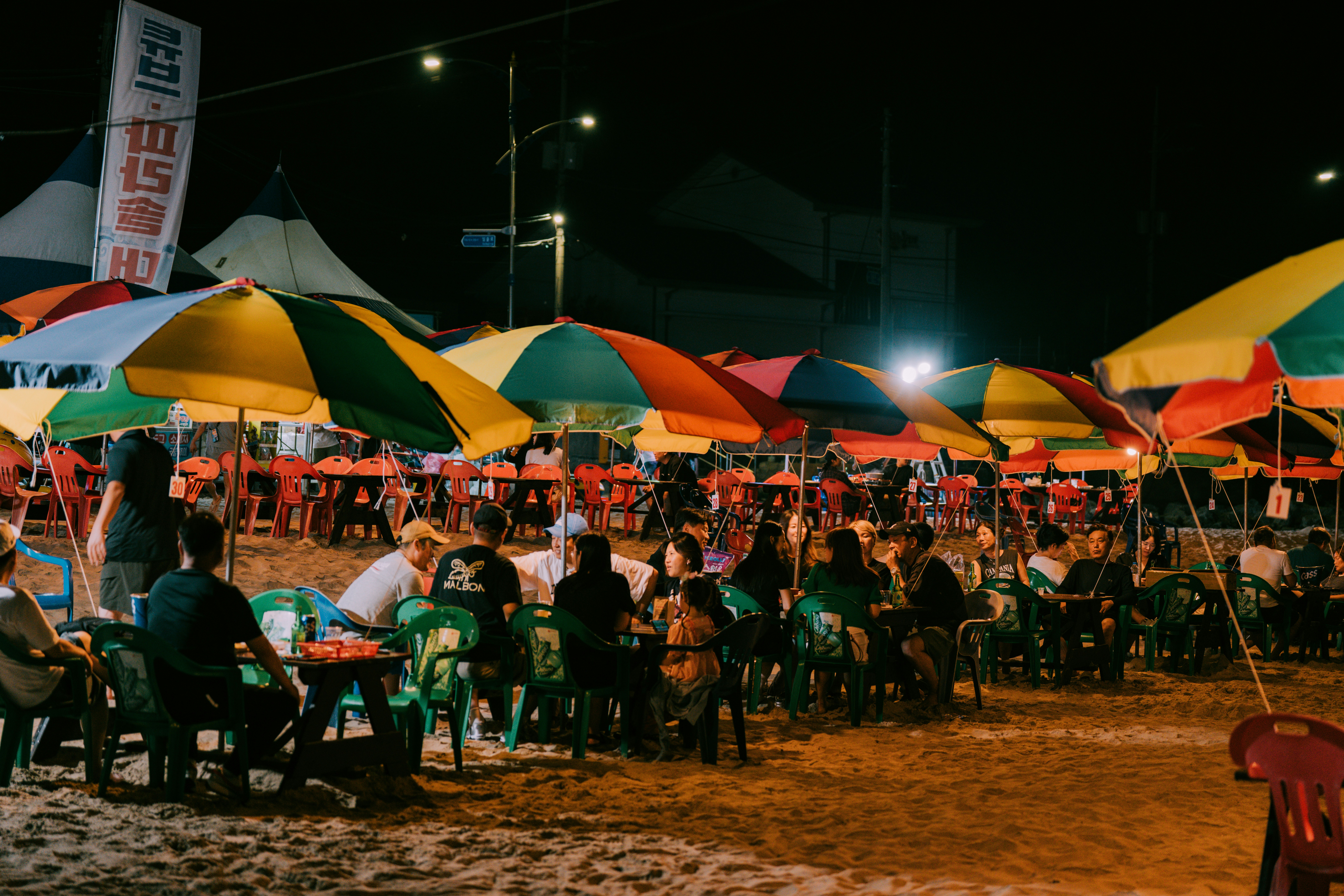 People dining under colorful umbrellas at night.