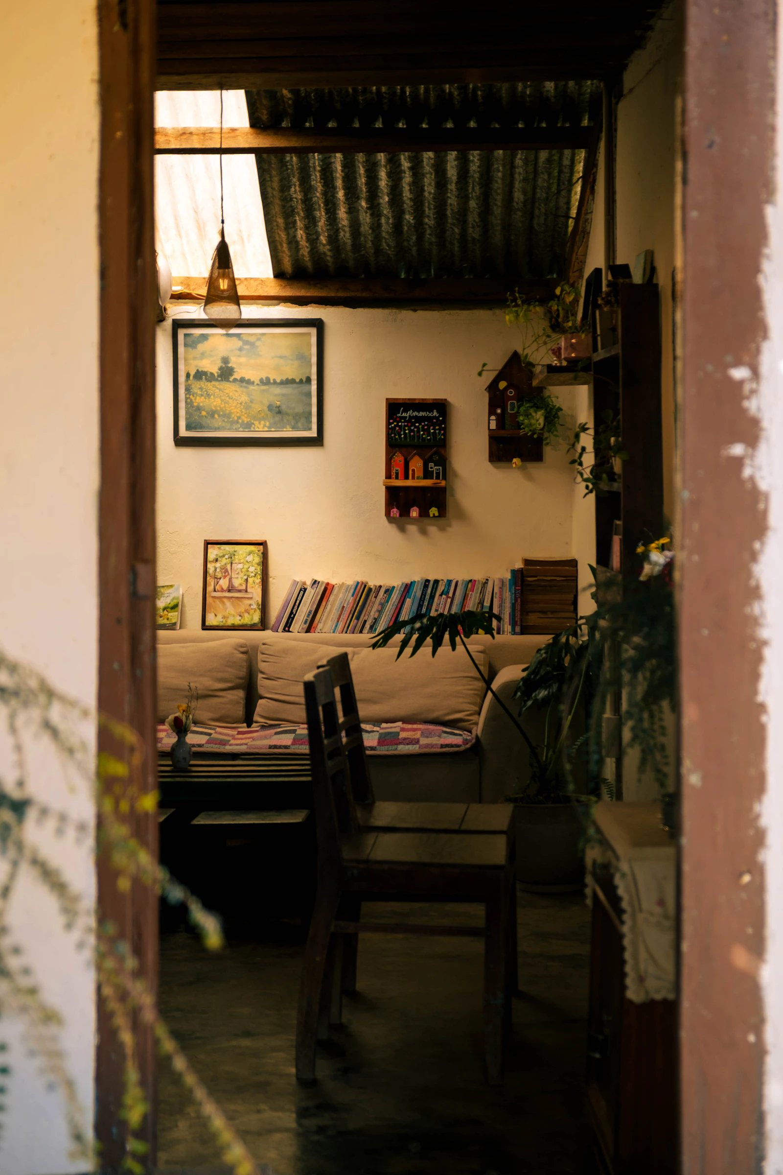 Bright, cozy living room with bookshelves, plants and a comfortable armchair