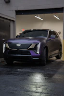 A sleek purple cadillac suv parked indoors.