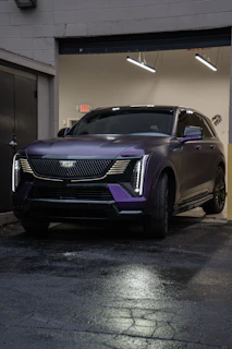 A sleek purple cadillac suv parked indoors.