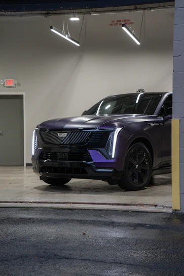 A sleek purple cadillac suv parked indoors.