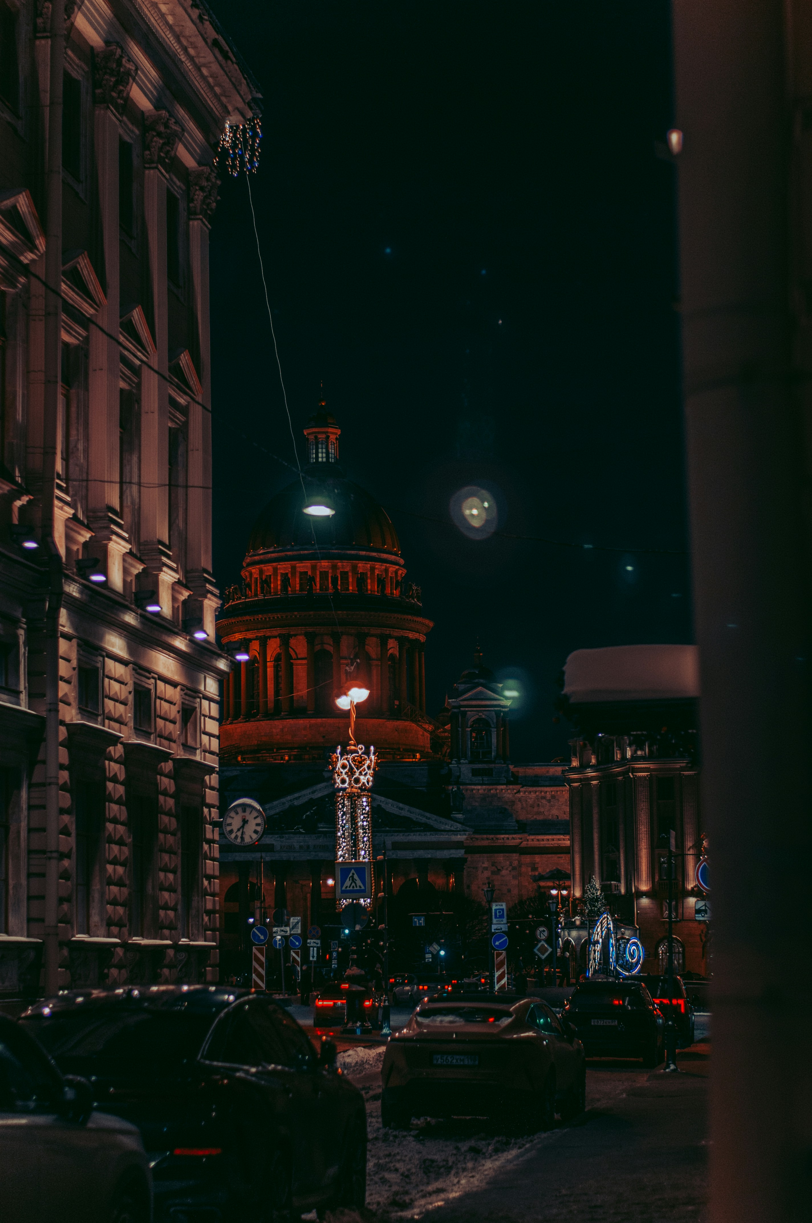 City street at night with illuminated buildings and cars.