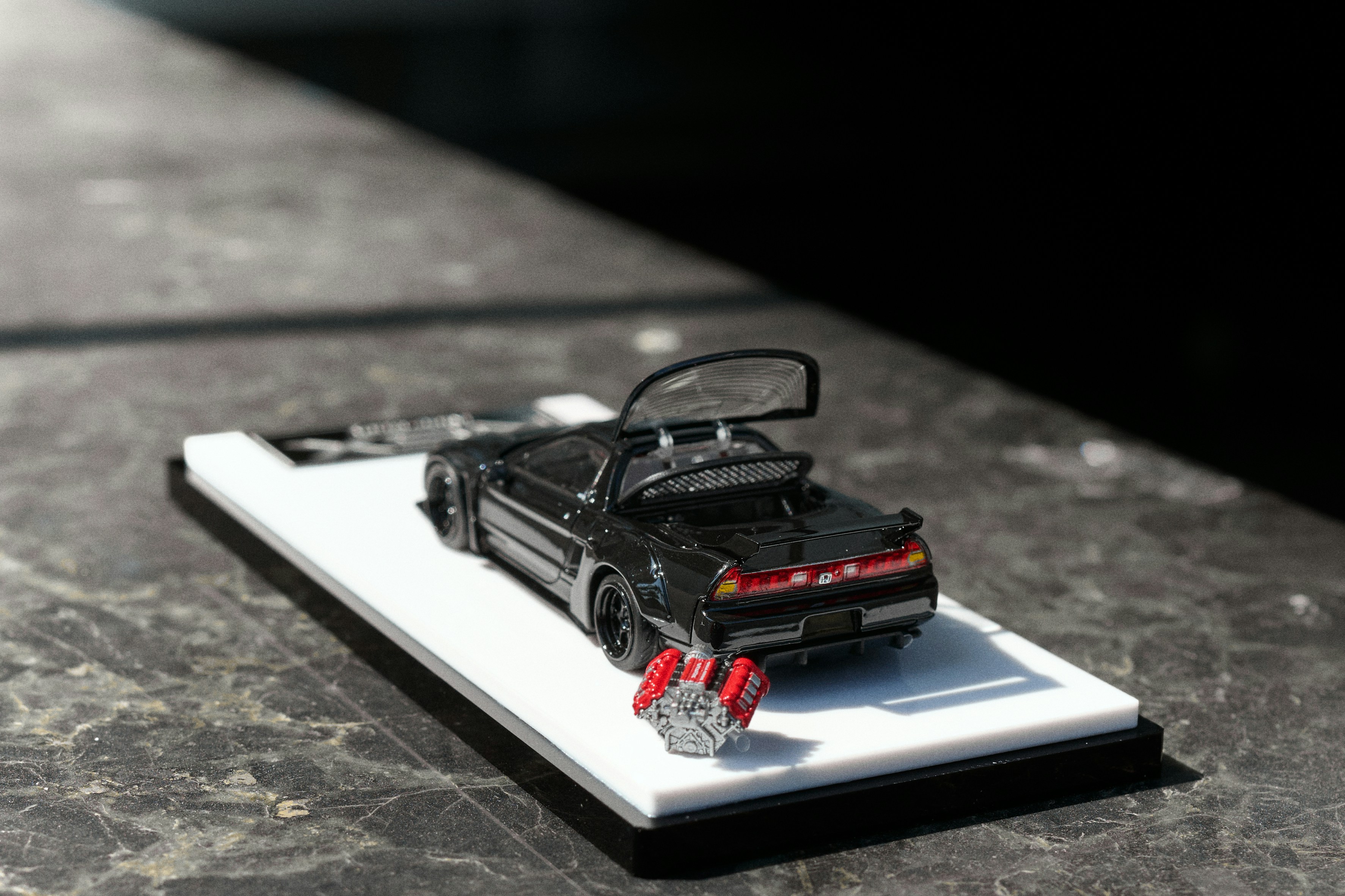 A miniature black delorean car on a display stand.