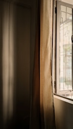 Sunlight streams through a window onto a curtain.