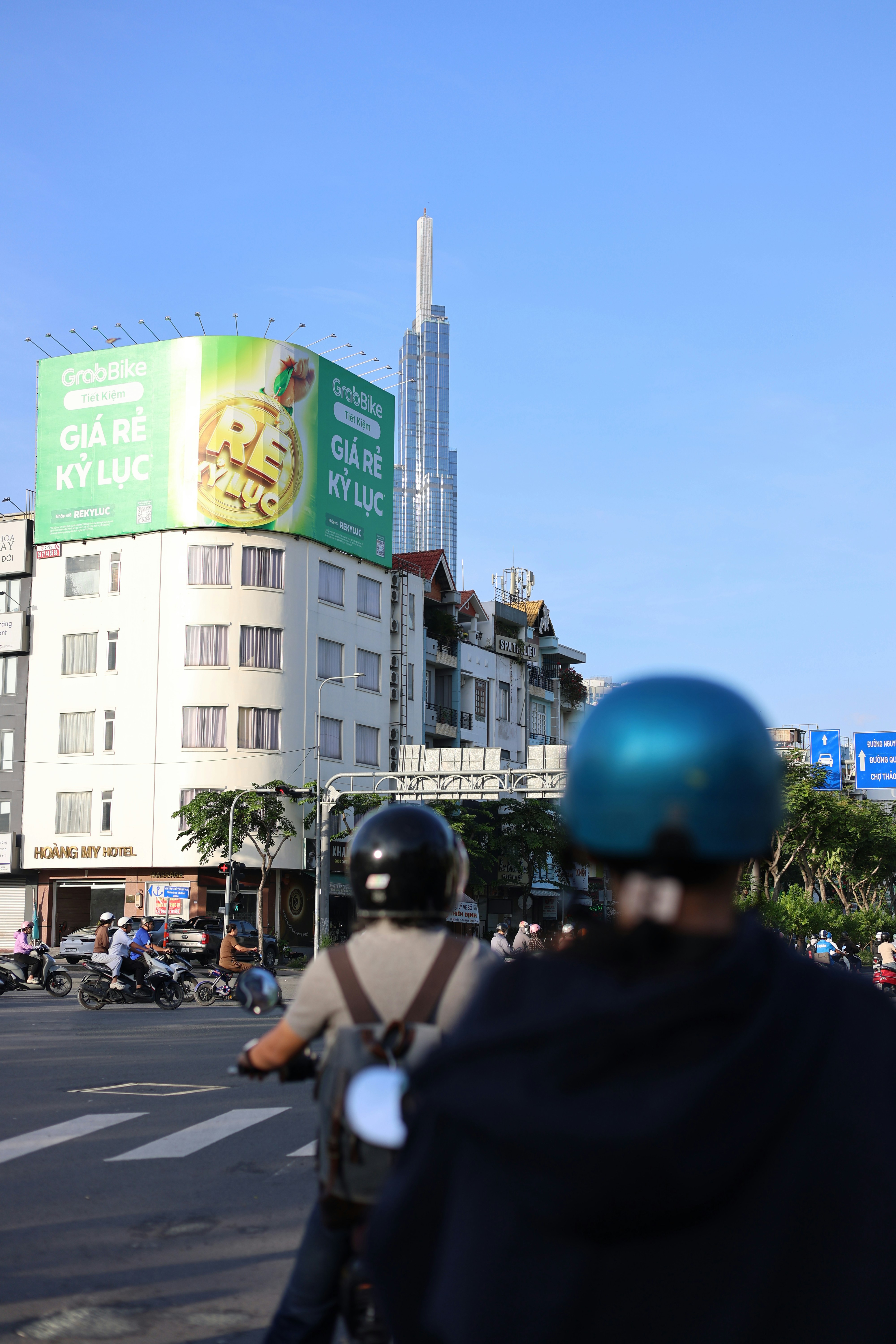 Motorcyclists on a street with tall buildings.