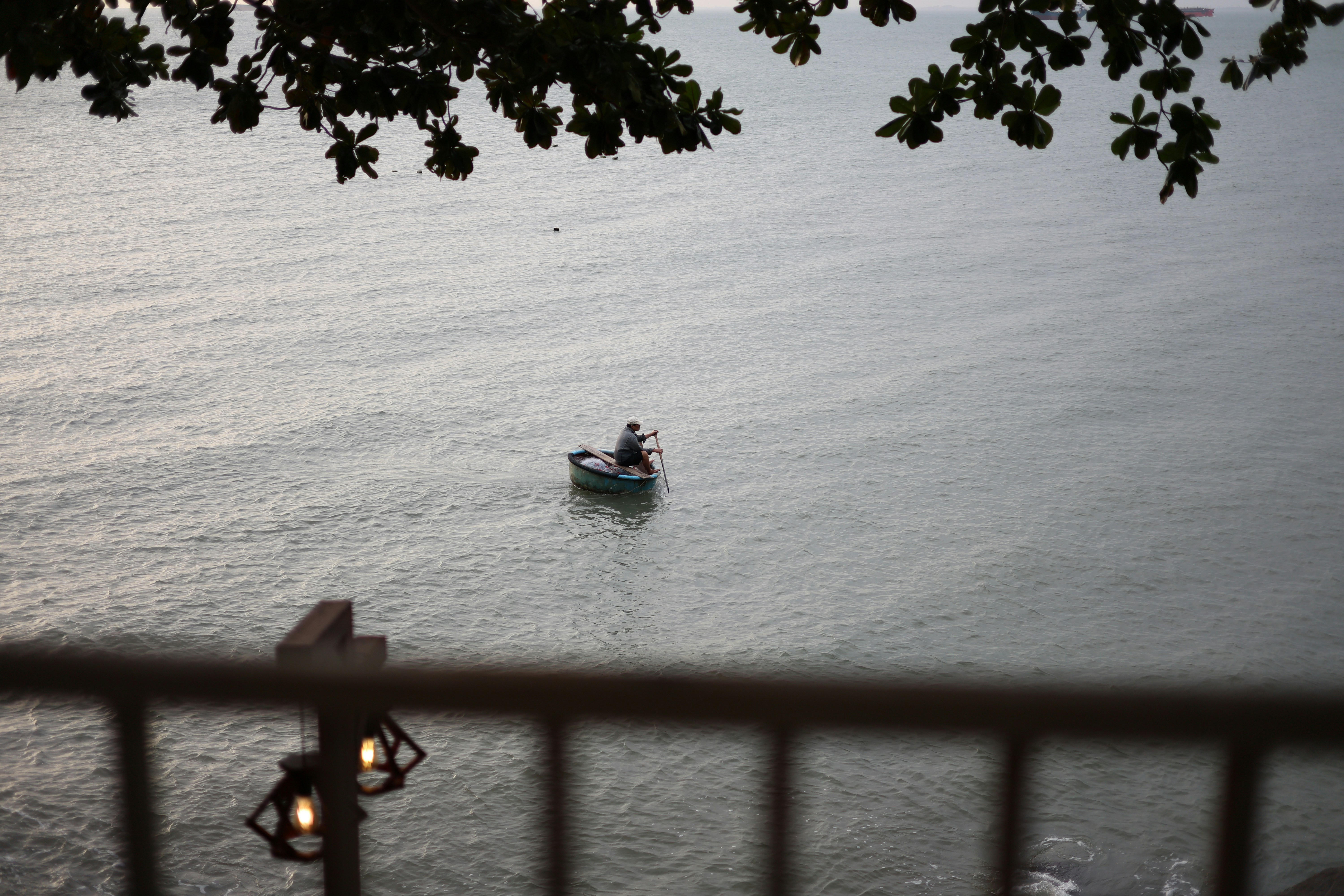 A person rows a small boat on a calm sea.