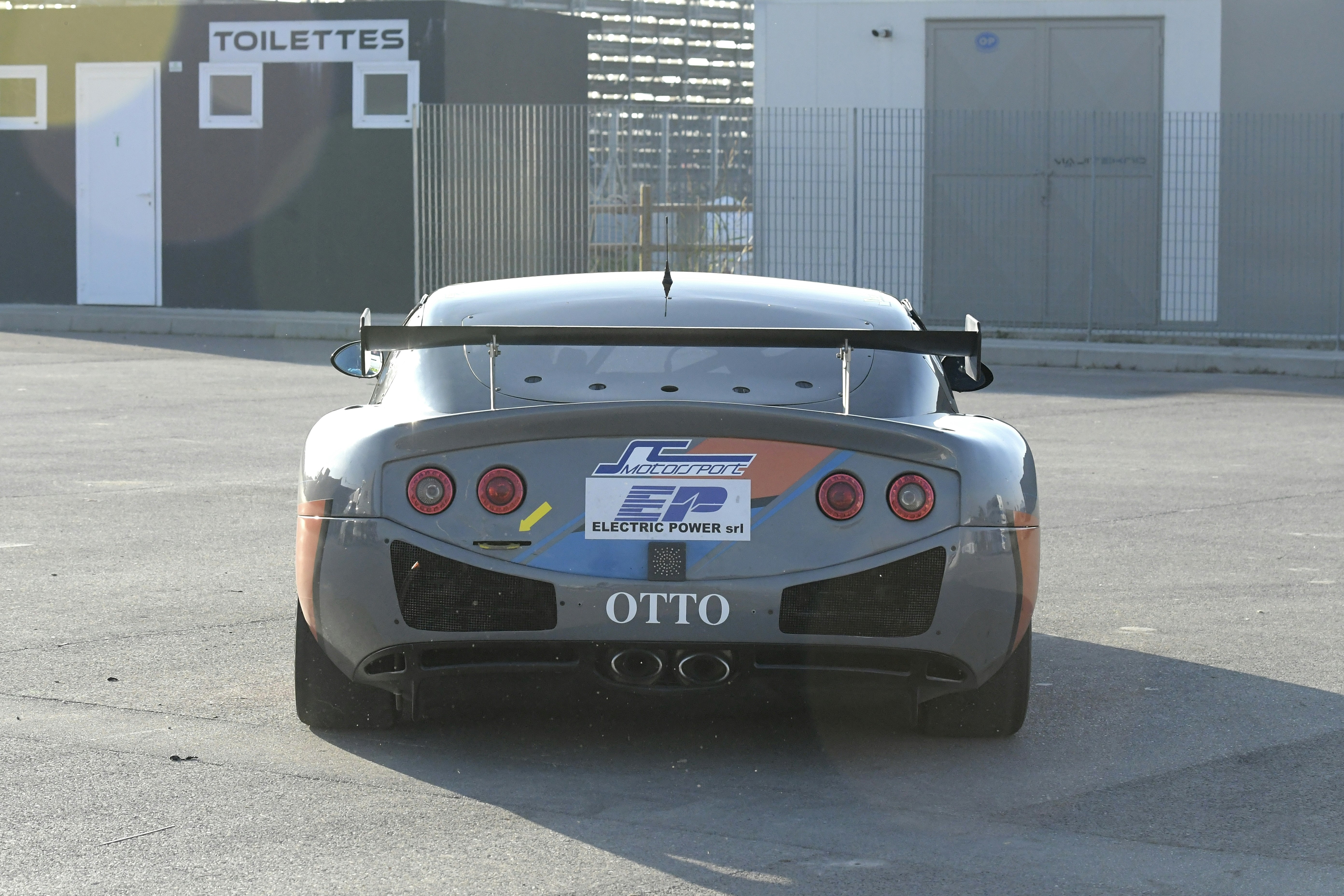 Rear view of a grey race car with racing decals.