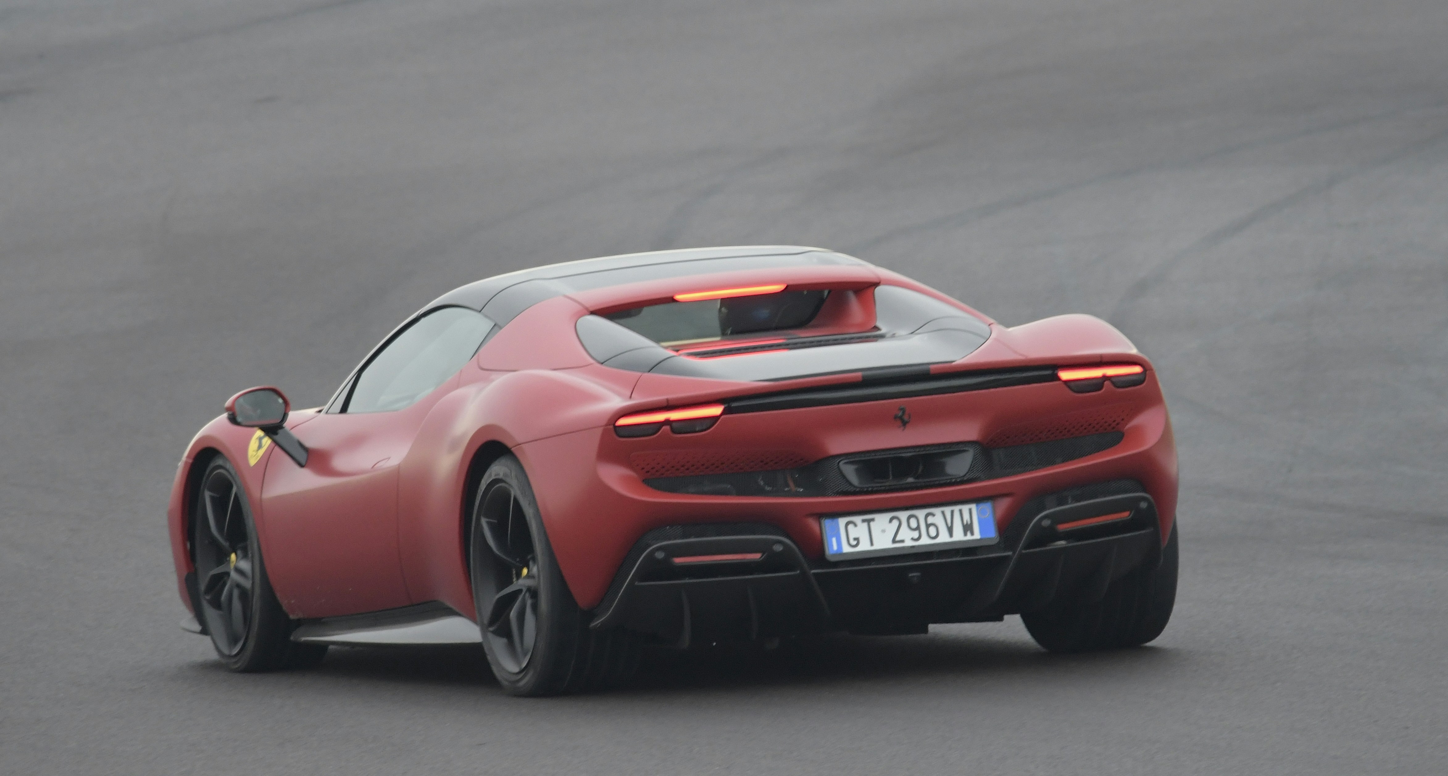 Red sports car driving on a wet track.