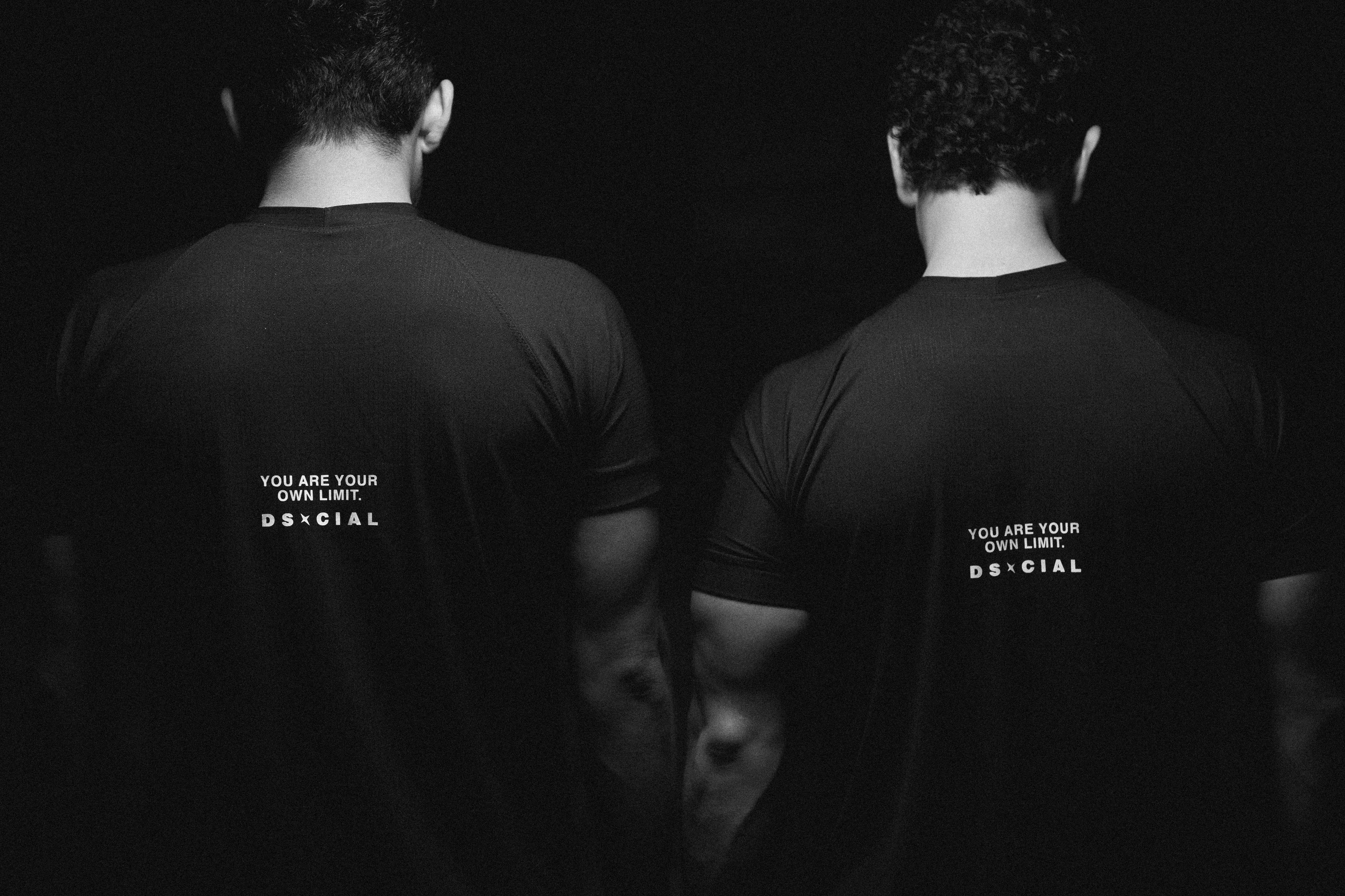 Two men wearing black t-shirts with white text
