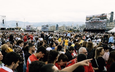 Large crowd watching a screen outdoors with a city skyline